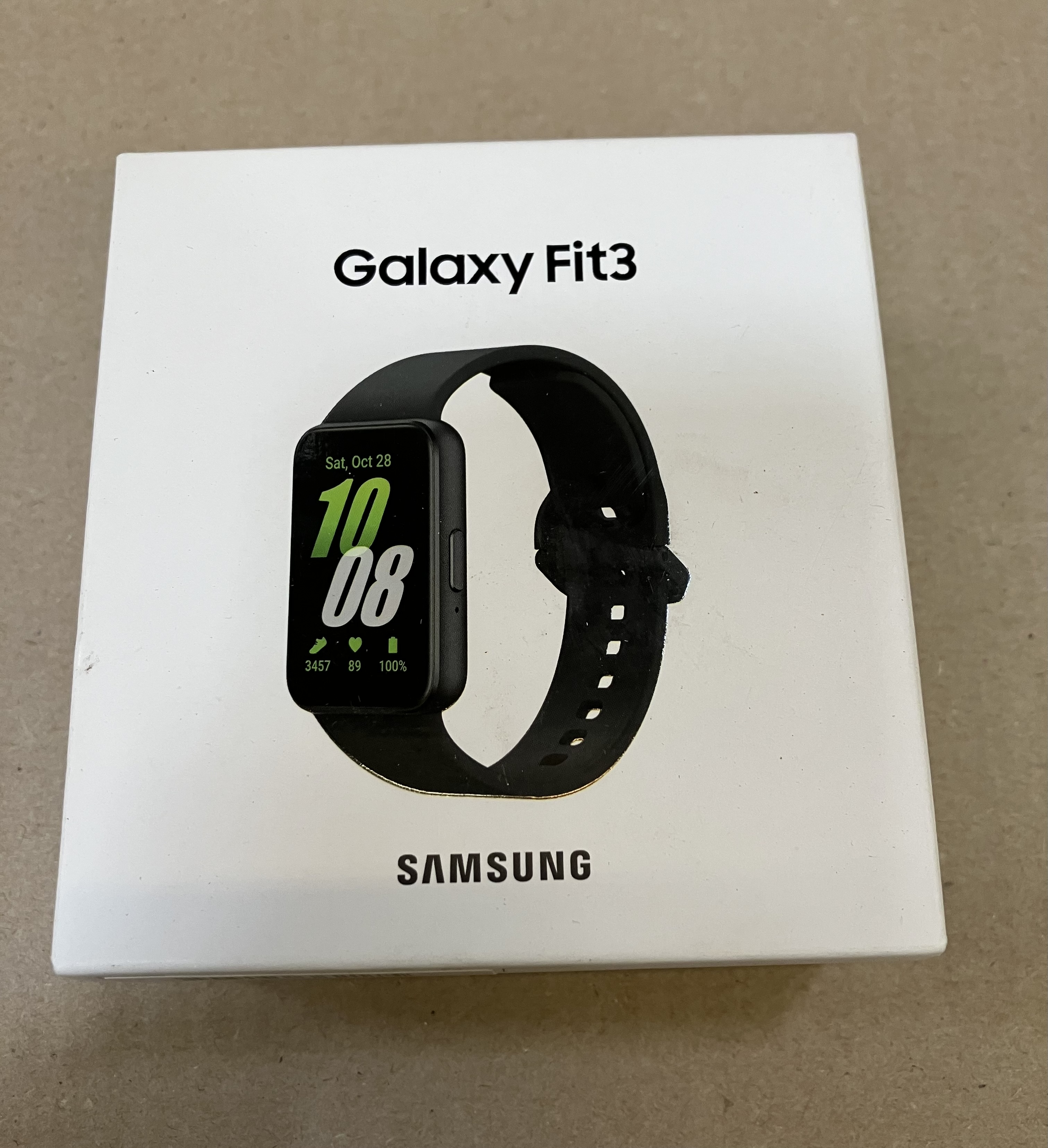 Pudełko Galaxy Fit3 z czarnym urządzeniem do śledzenia aktywności fizycznej z przodu, wyświetlającym czas i statystyki.