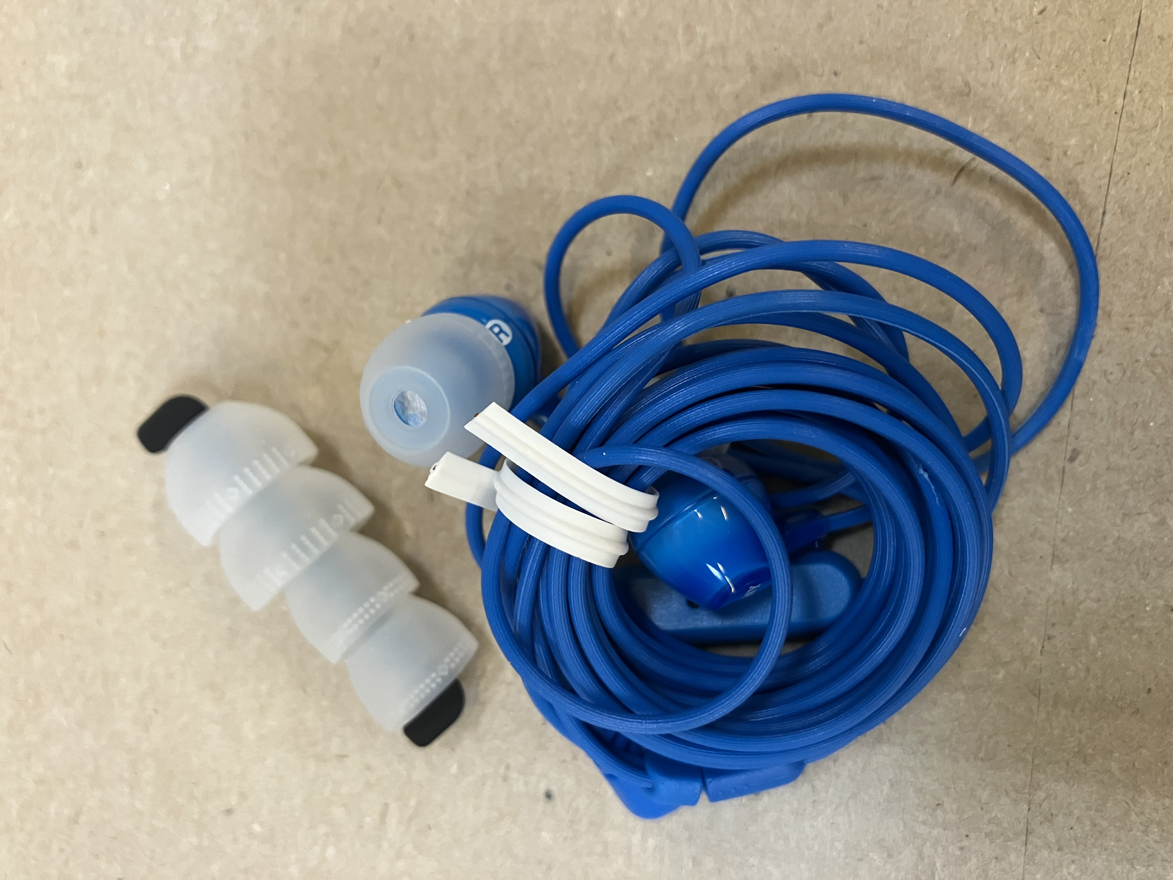 Słuchawki douszne i niebieski kabel. Białe, niebieskie wkładki douszne i czarno-białe separatory.