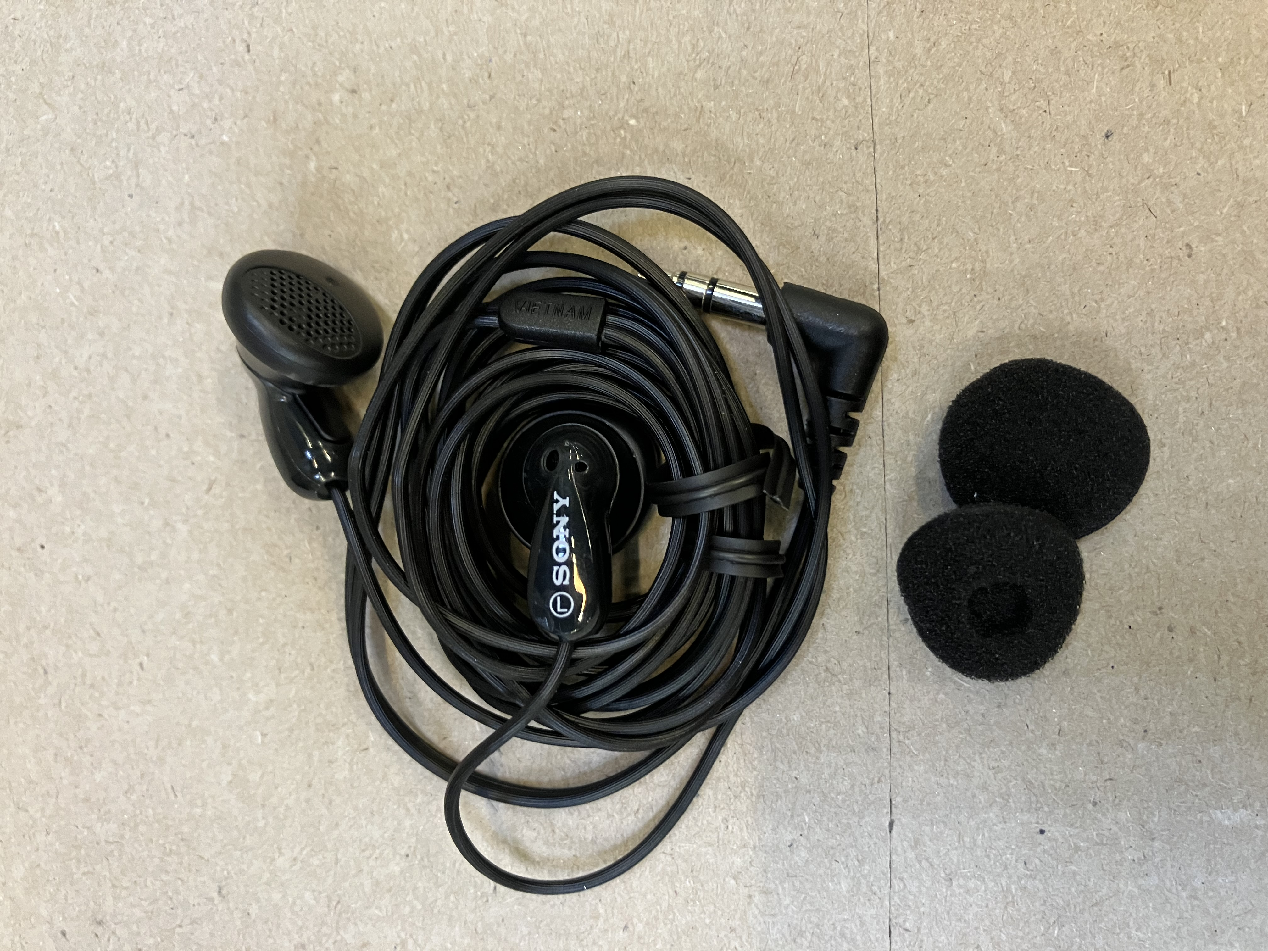 Czarne słuchawki Sony z przewodem i dwiema zapasowymi osłonami słuchawek.