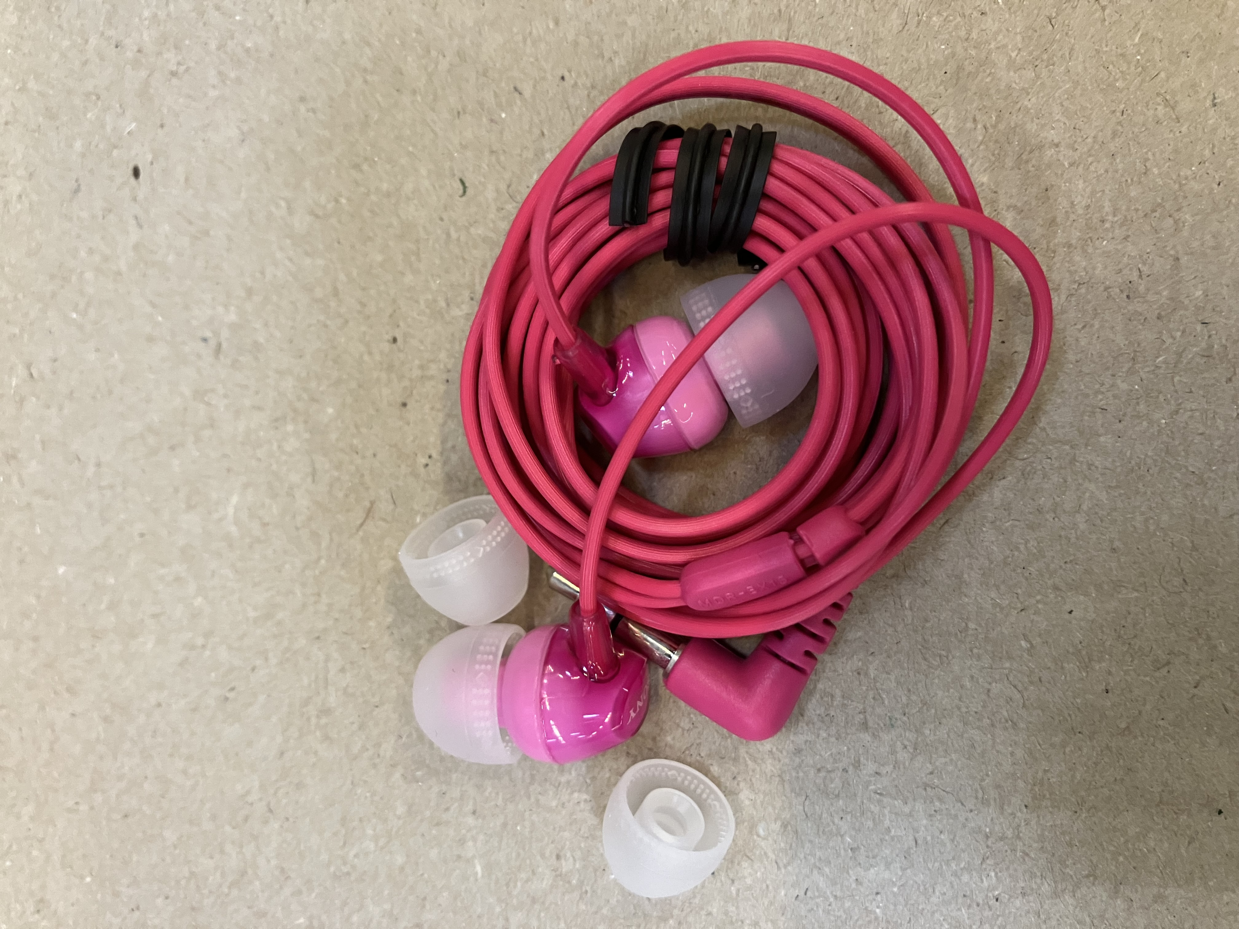 Różowe słuchawki z różowym przewodem i białymi nakładkami na słuchawki.