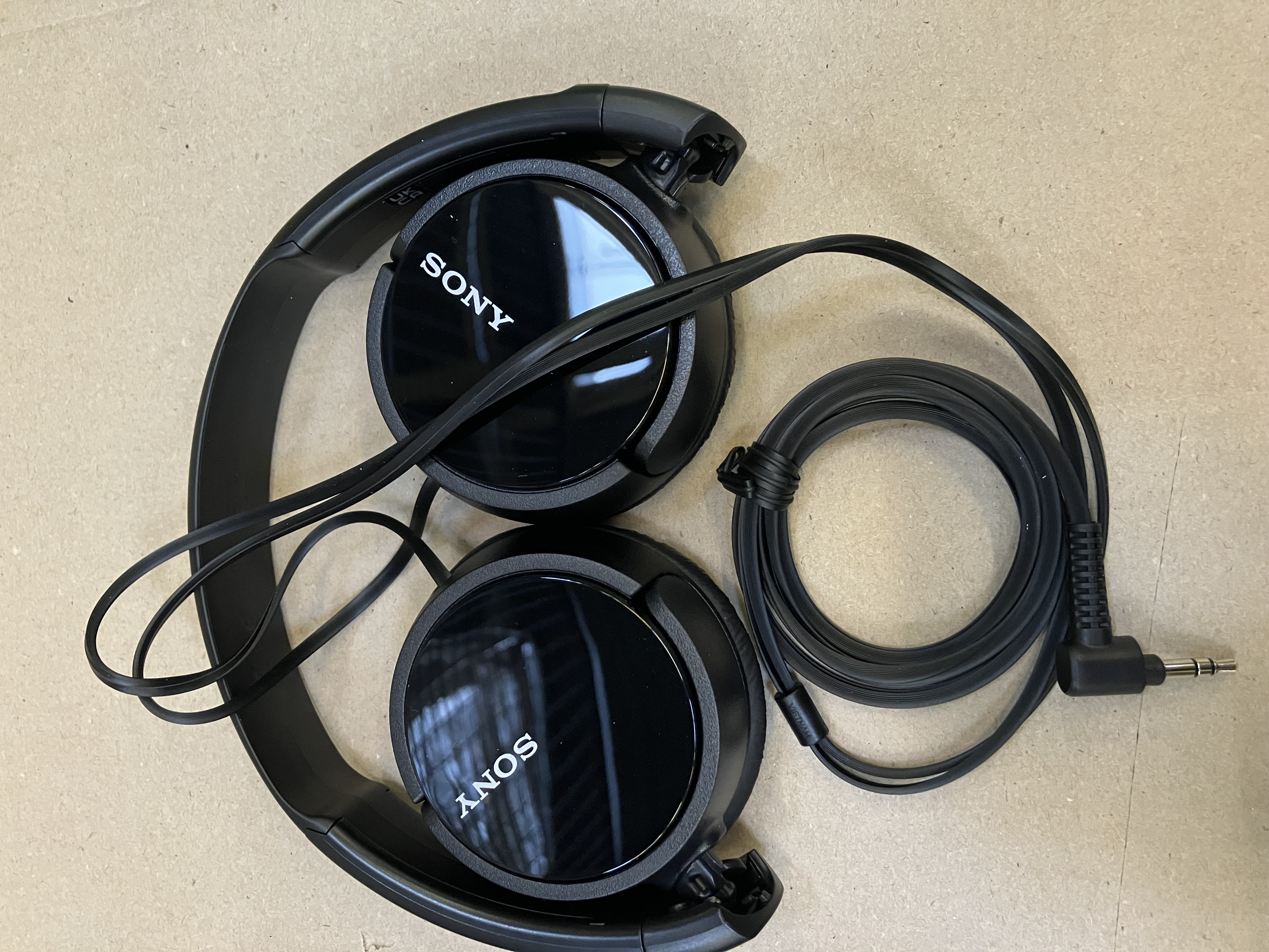 Składane czarne słuchawki z czarnym kablem i wtyczką 3,5 mm.