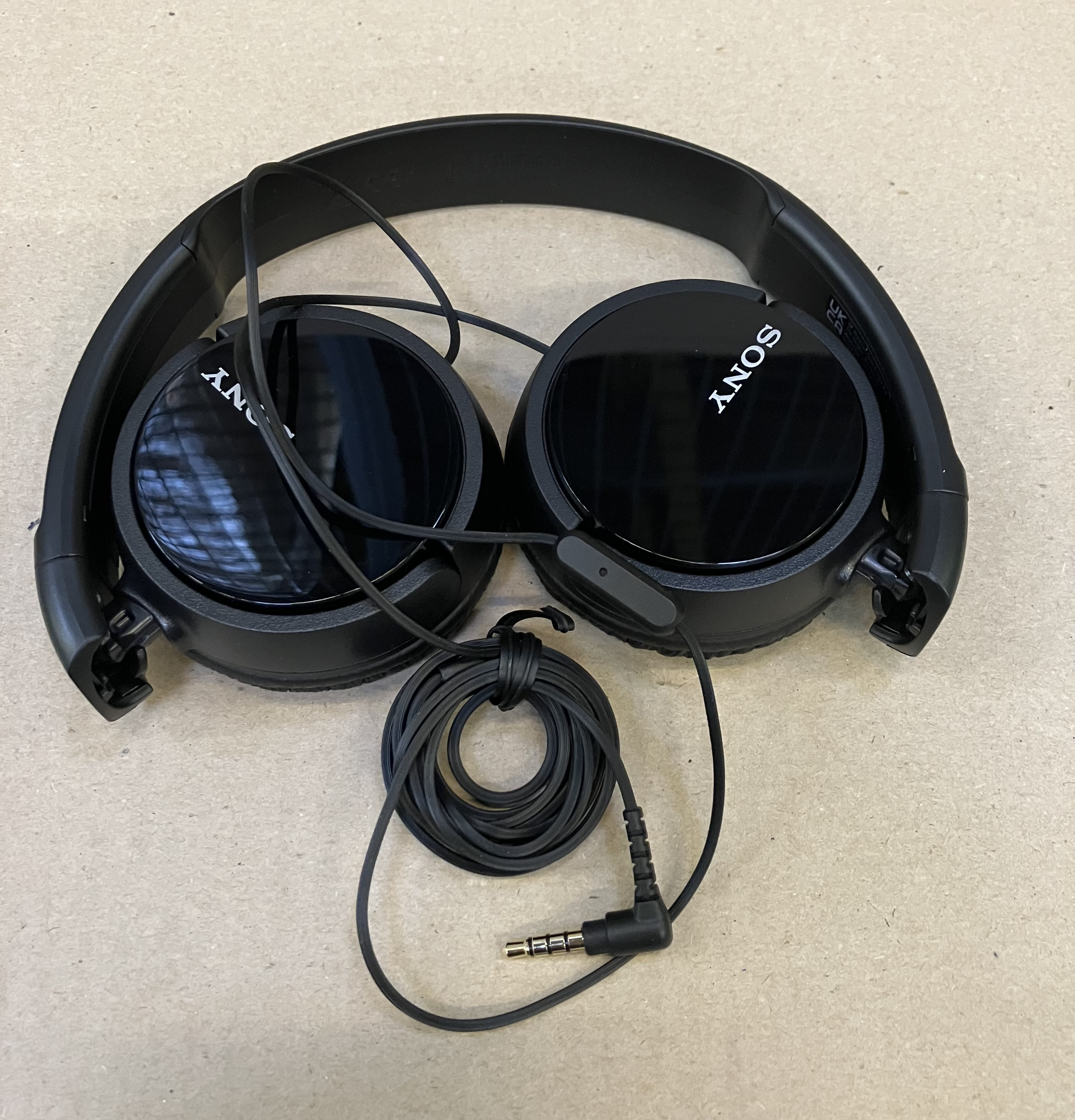 Czarne, złożone słuchawki z kablem i wtyczką jack.