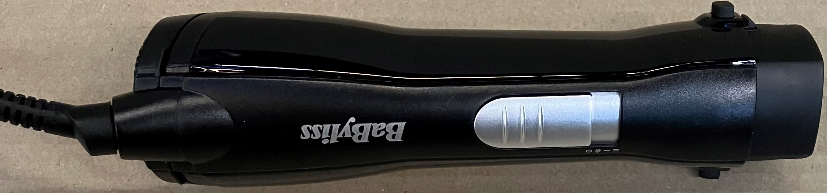 Czarna lokówka Babyliss ze srebrnym przełącznikiem i kablem.