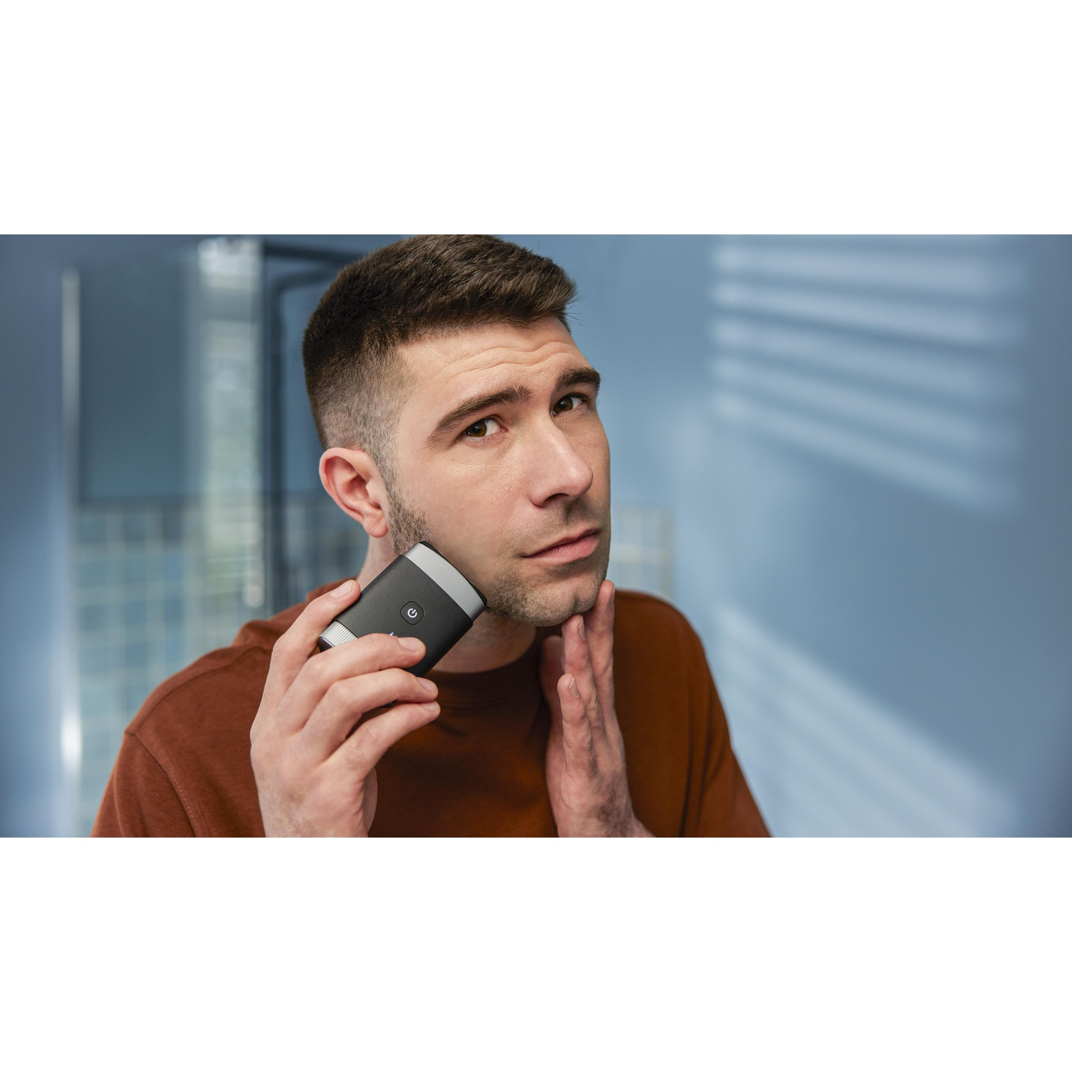 Man shaving his face with a black and gray electric shaver.