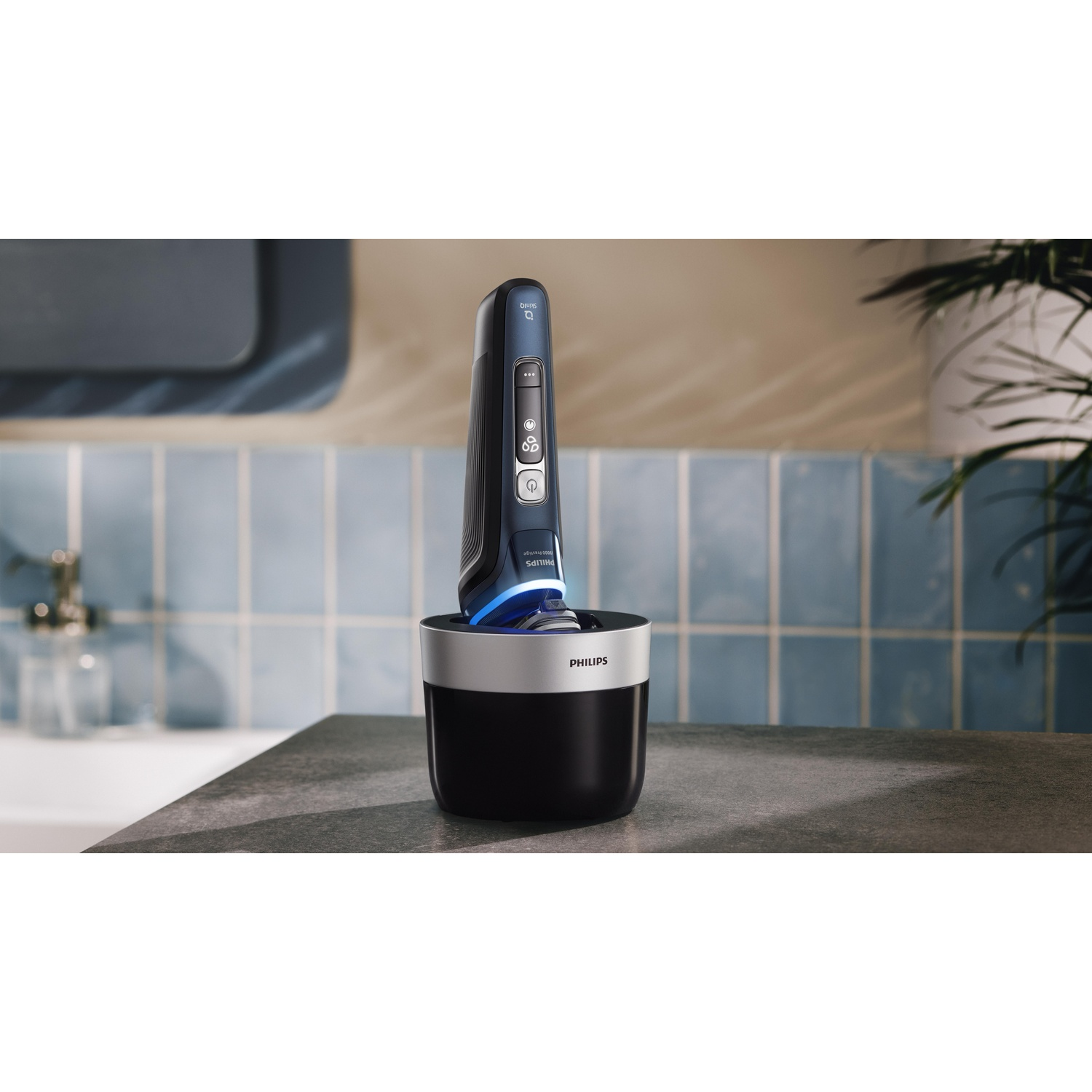 Een zwarte en blauwe Philips scheerapparaat in de oplader. De scène speelt zich af op een grijs aanrecht.