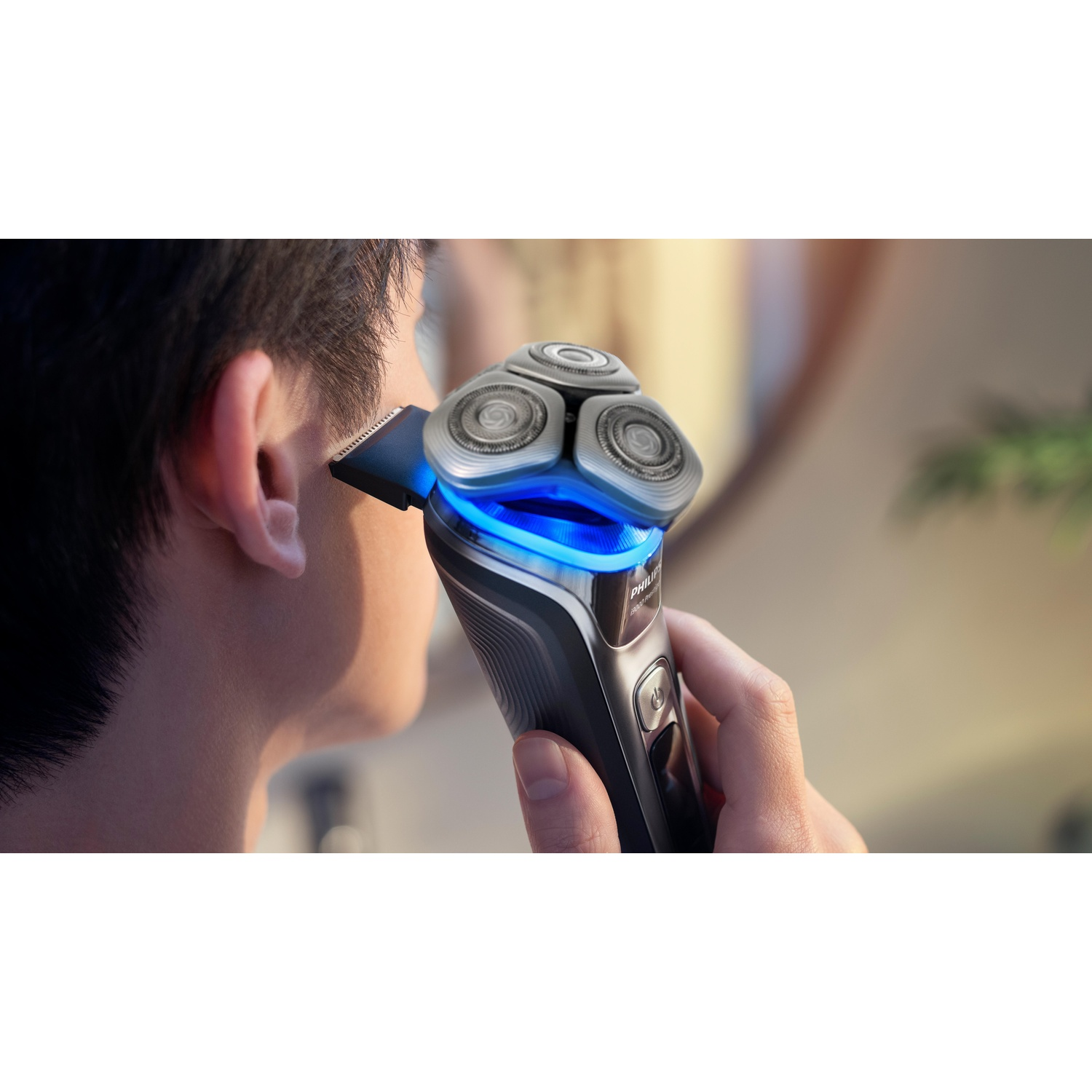 Man shaves with a Philips electric shaver, close up shows shaving heads and beard.