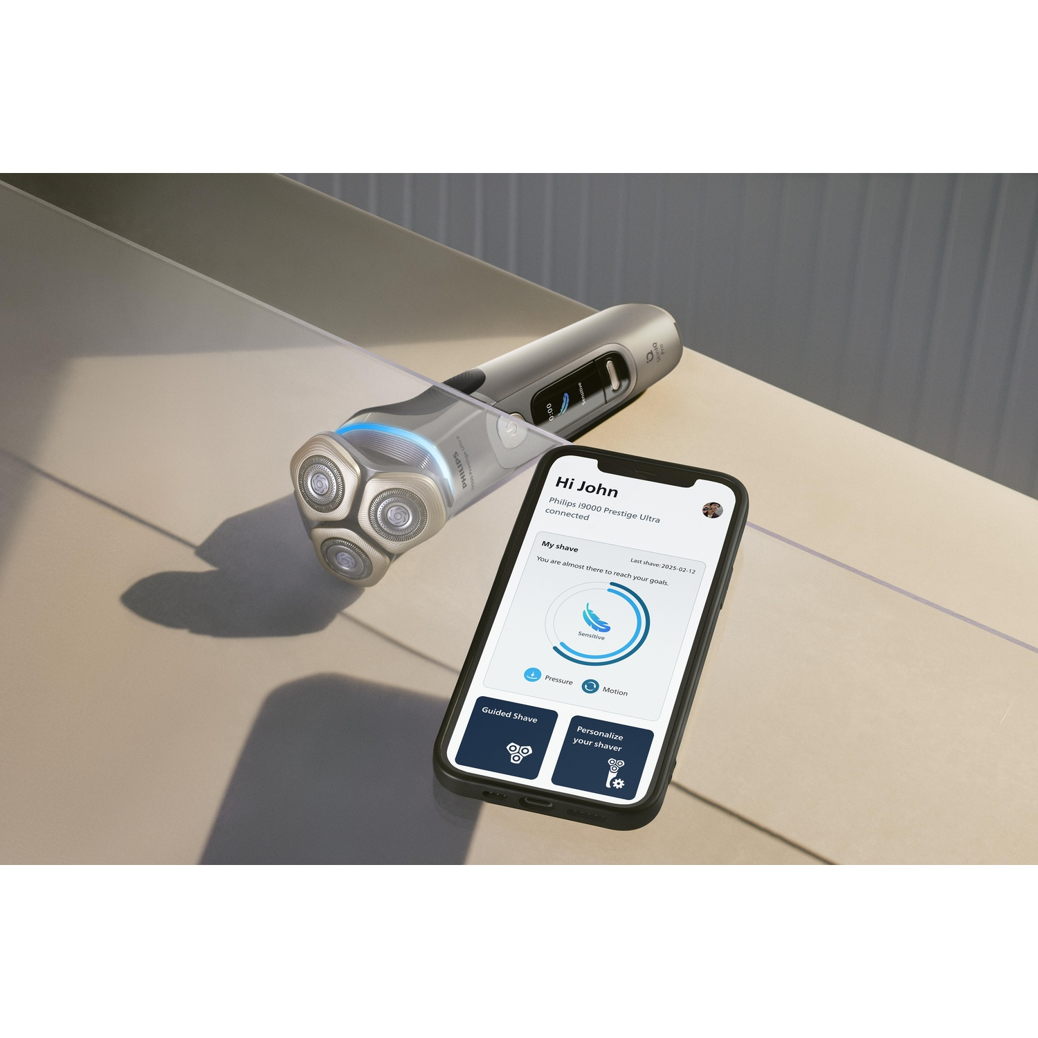 A silver shaver and a smartphone displaying shave information and smart functions are on a surface.