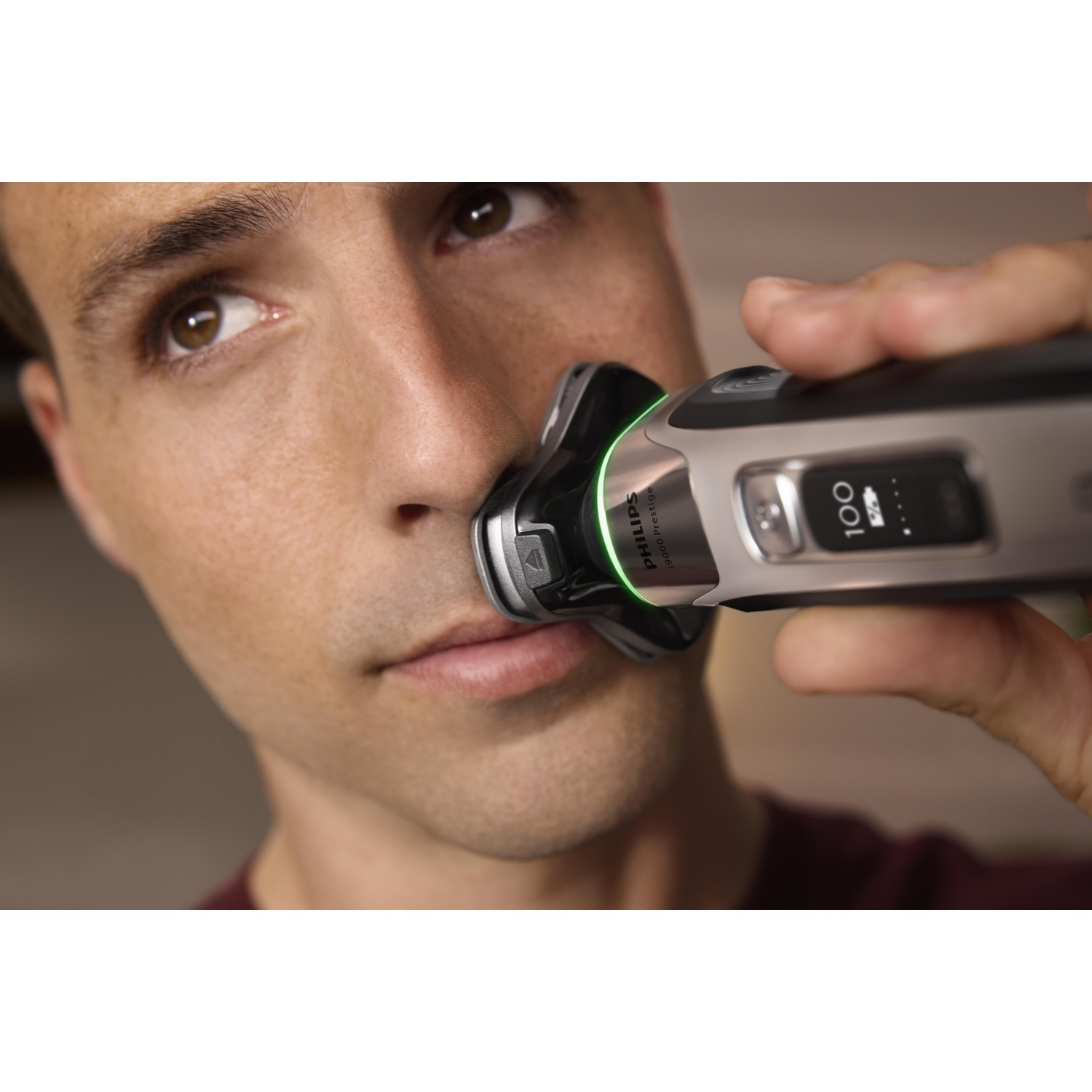 Man shaving his face with a silver and black electric shaver, close up shot.