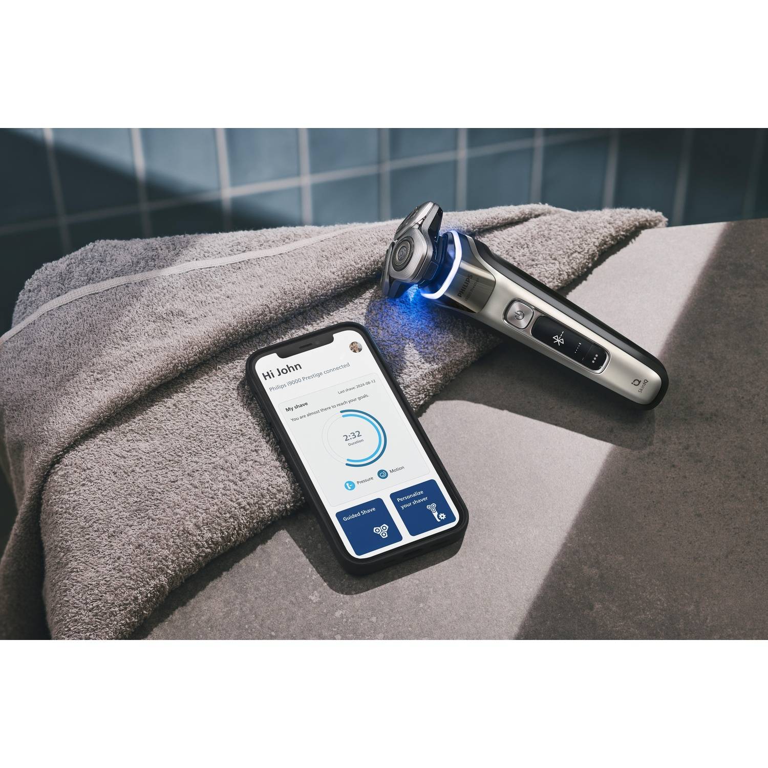 Electric shaver, phone with app, and towel. Bathroom setting.