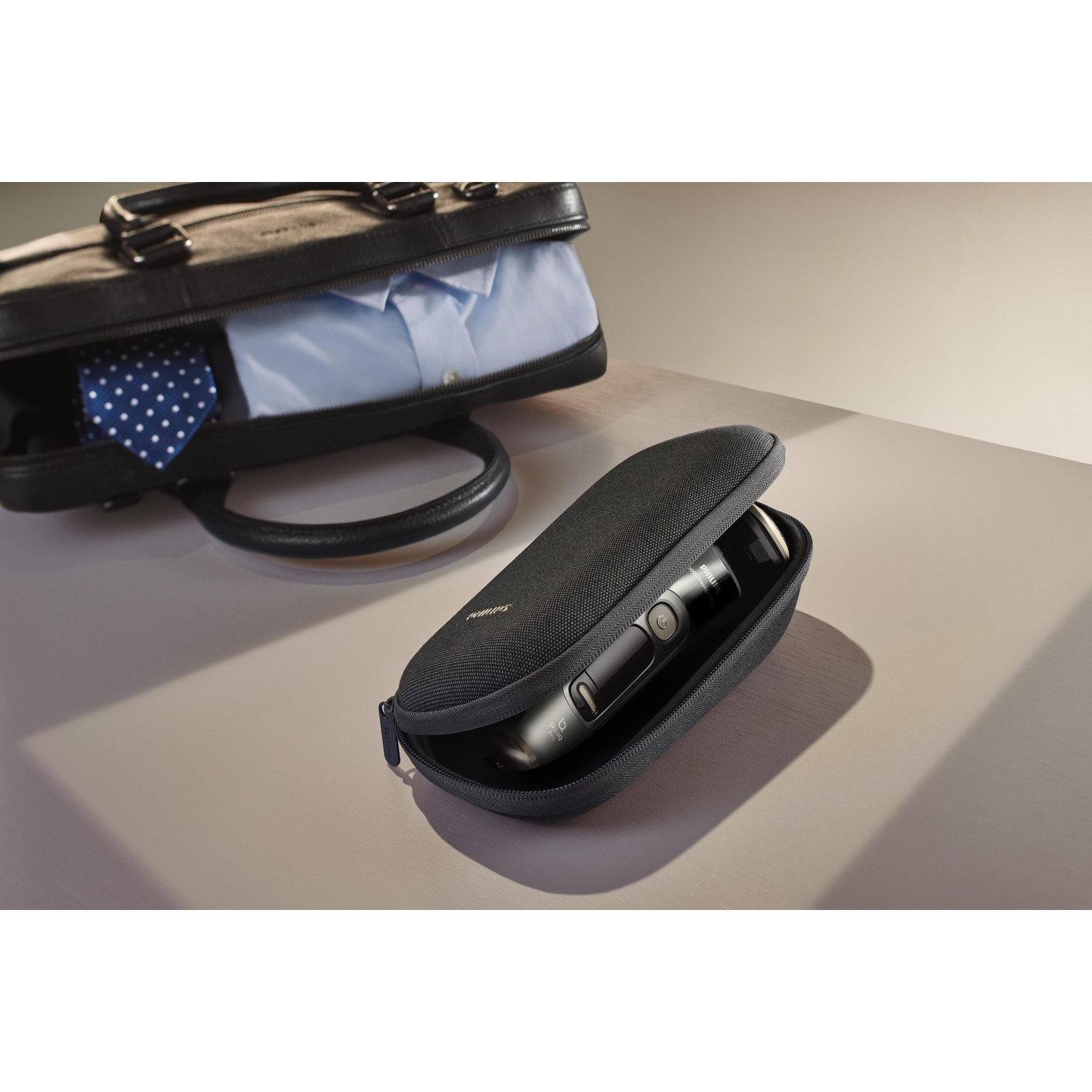 A black travel case with a shaver and a shirt inside a bag.