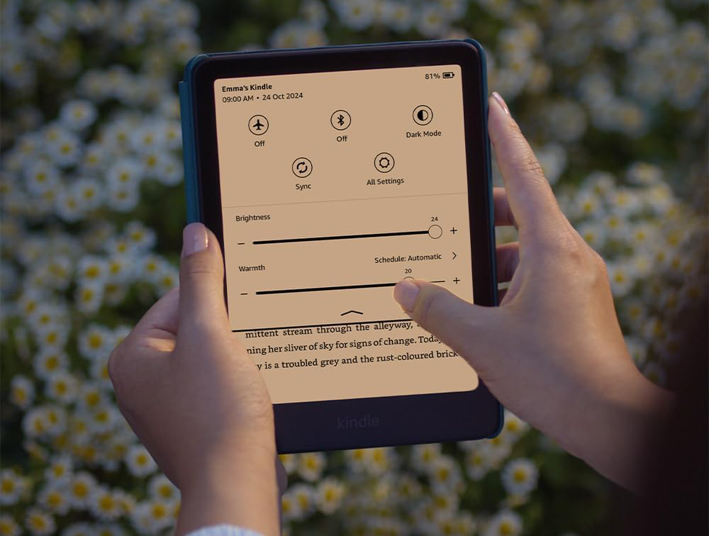Egy személy egy Kindle-t tart. A képernyő a fényerő és a melegség beállításait mutatja.