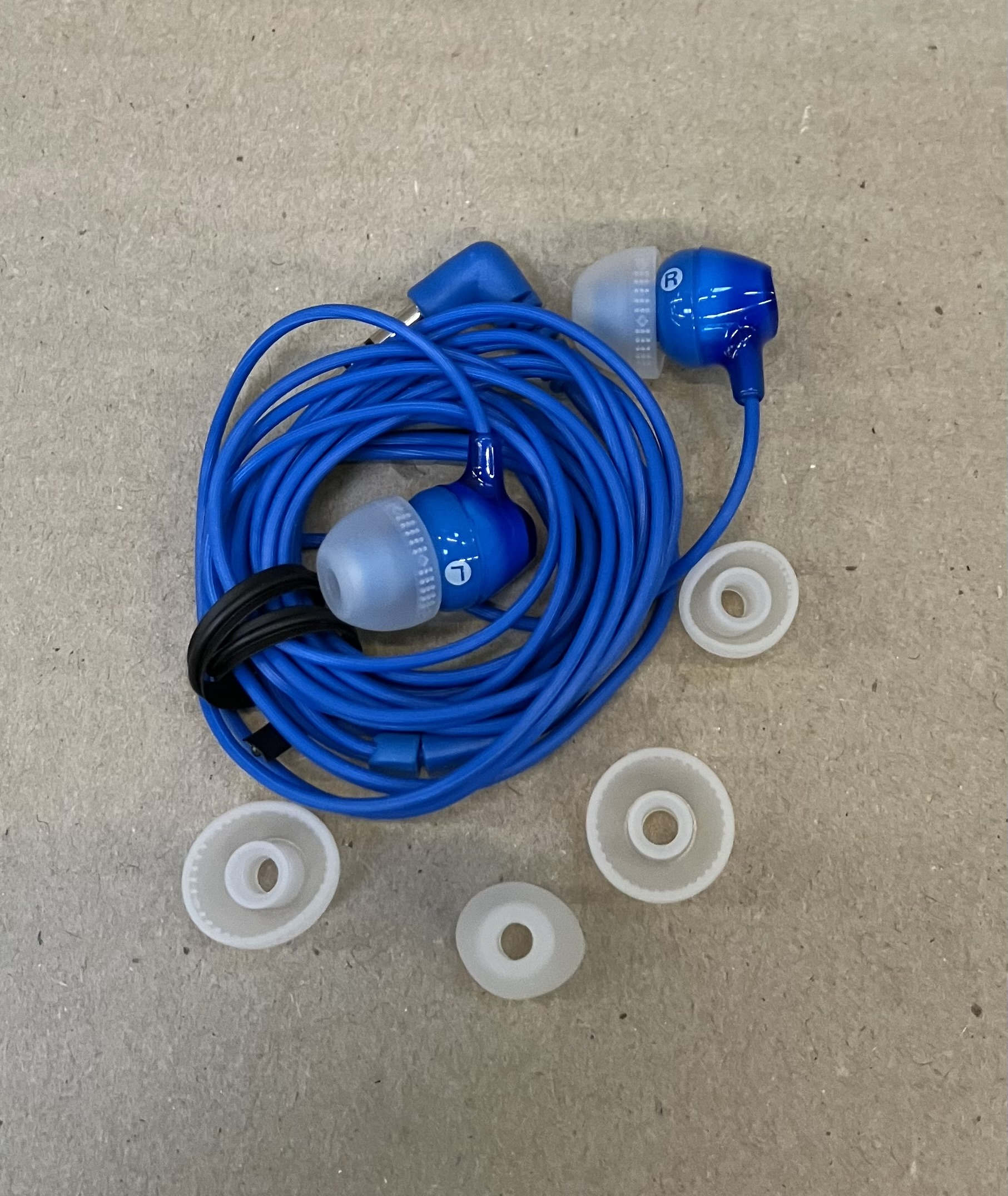 Niebieskie słuchawki z niebieskim kablem i kilkoma wkładkami dousznymi na powierzchni.