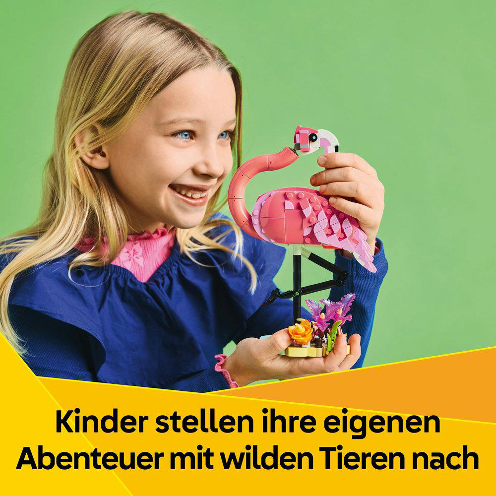 Ein junges Mädchen lächelt, während es ein LEGO-Flamingo-Spielzeug hält. Text: Kinder stellen Abenteuer mit Tieren nach.