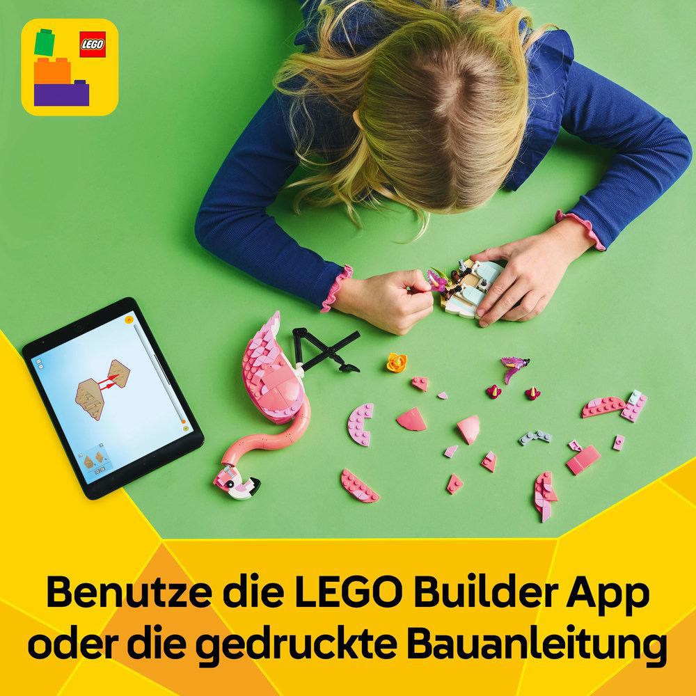 Ein Mädchen baut einen rosa LEGO-Flamingo zusammen. Ein Tablet zeigt Anweisungen auf grünem Untergrund.