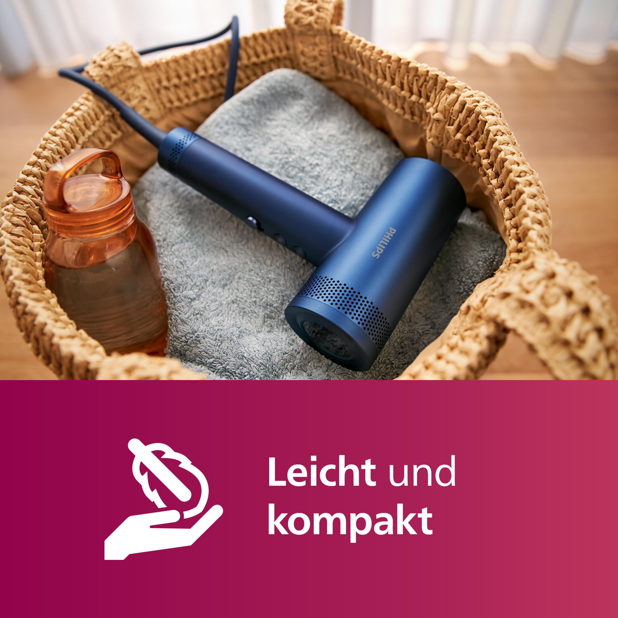 Blauer Haartrockner in einem Korb, orangefarbene Flasche.