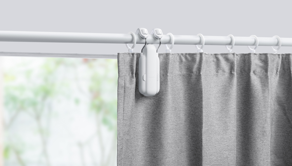 Ein Smart-Home-Gardinensystem mit weißer Schiene, grauen Vorhängen und weißen Bedienelementen.