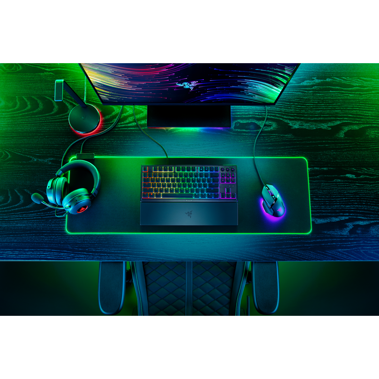 Gaming setup with a monitor, keyboard, mouse, and headset on a dark wooden desk.