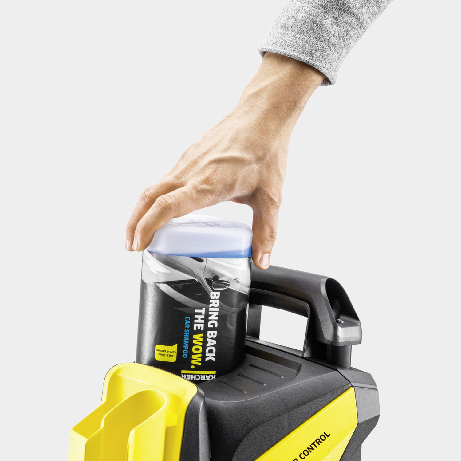 Main tendant la main vers une bouteille de shampoing sur un appareil noir et jaune.
