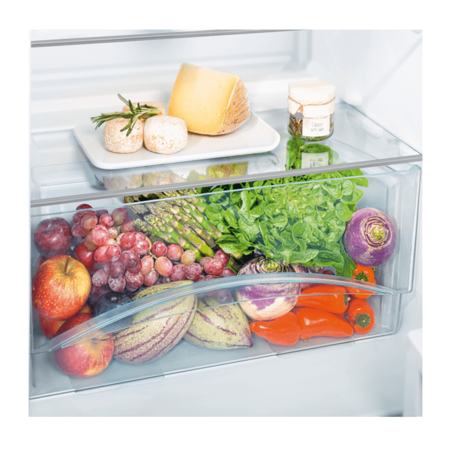 A refrigerator drawer with fresh produce: fruits, vegetables, and cheese.