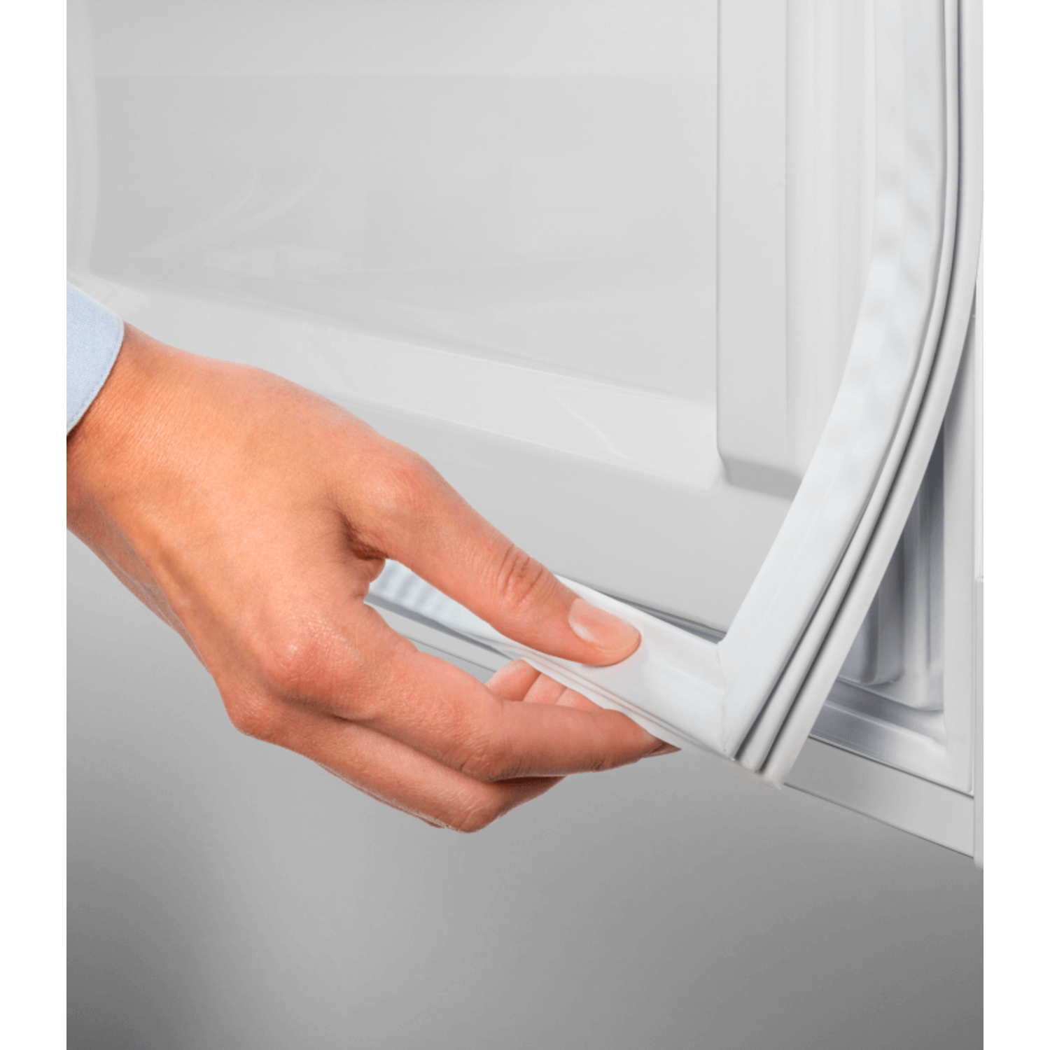 A hand pulling away a white rubber seal from a white appliance.