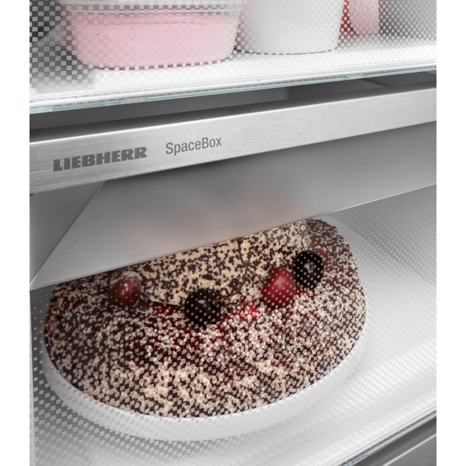 Cake in a refrigerator. It has chocolate topping and cherries.
