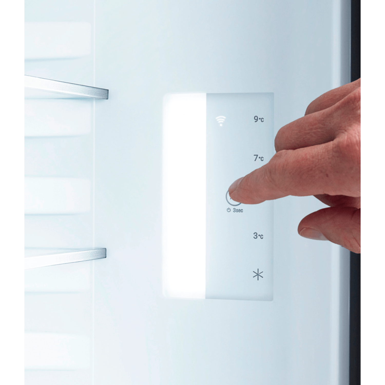 A hand pressing a button on a fridge control panel. Temperatures displayed.
