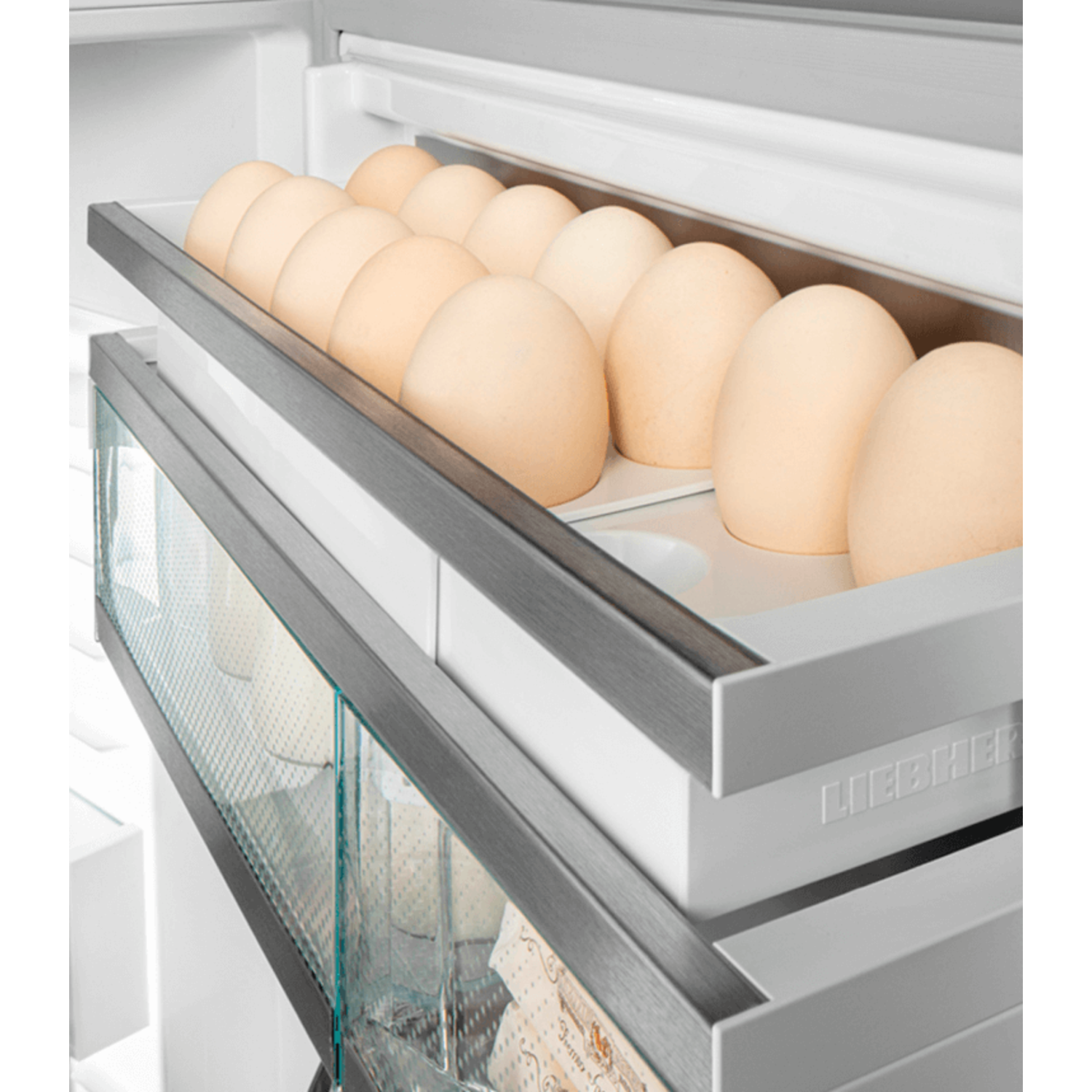 A refrigerator drawer holding several beige eggs.