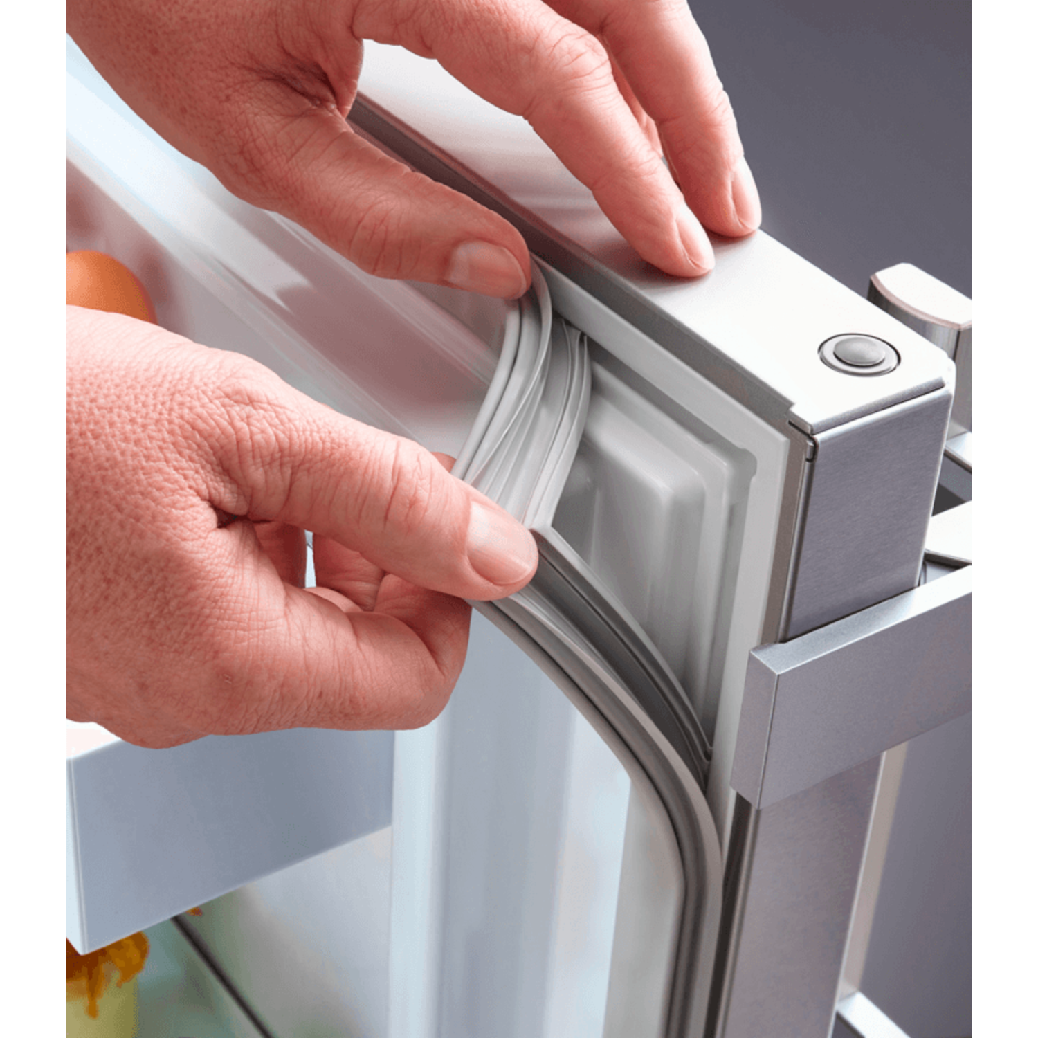 Hands pulling a refrigerator door seal. Silver fridge, black background, and an egg is visible.