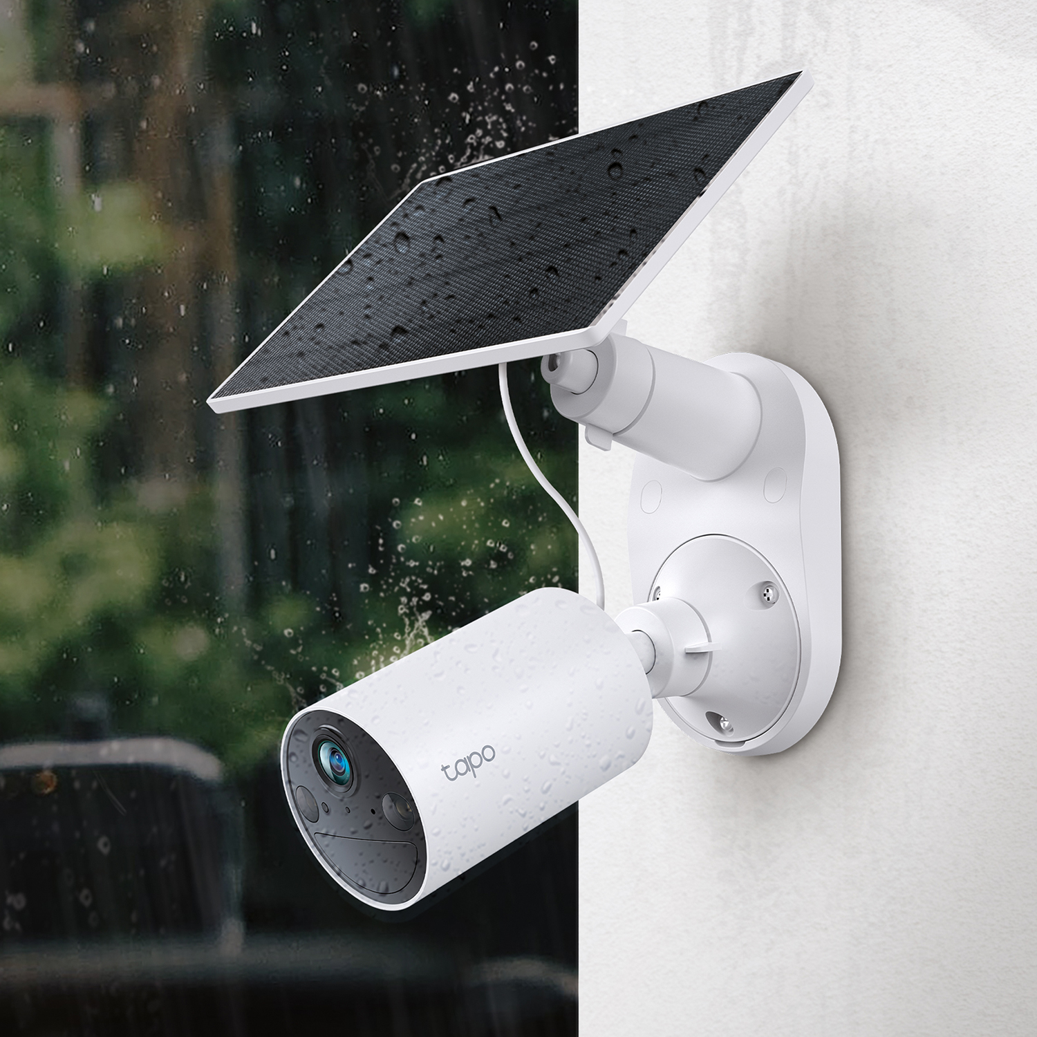 Una telecamera di sicurezza bianca con un pannello solare. Montata su un muro in un ambiente piovoso.