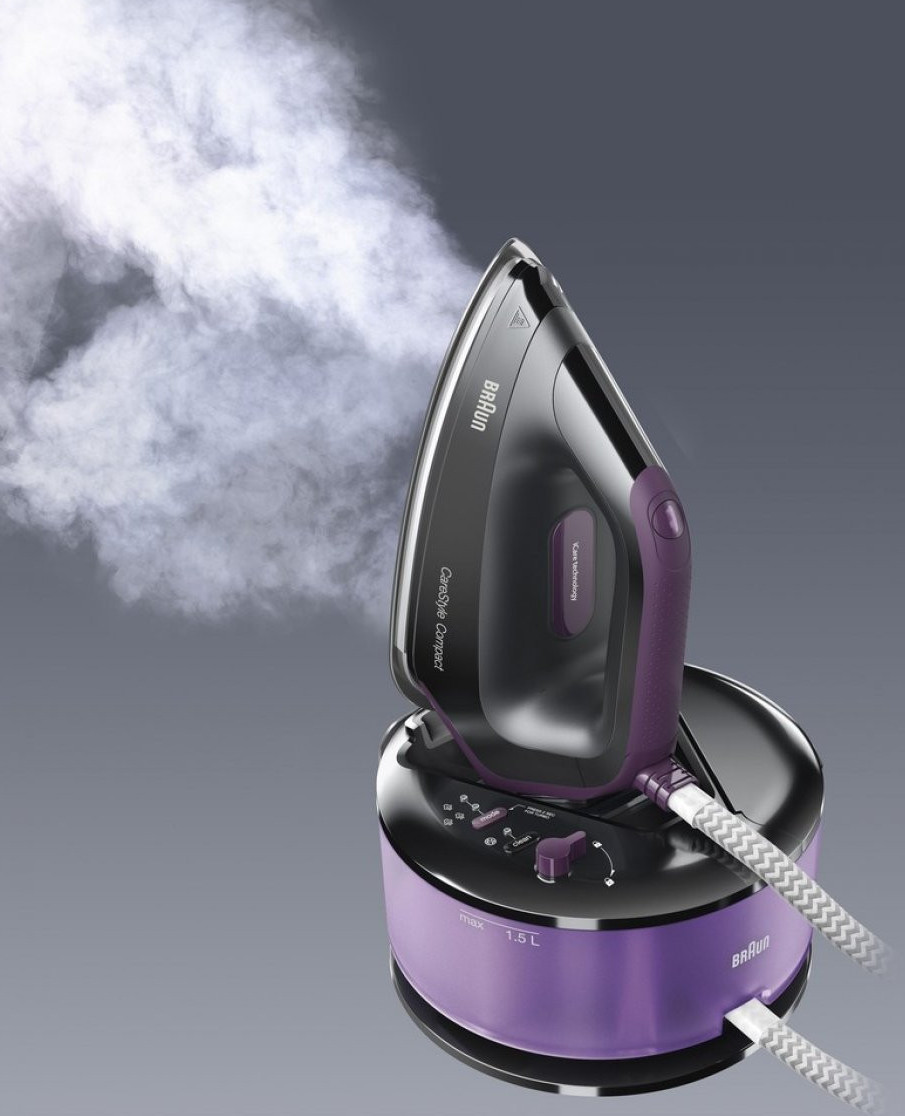 Fioletowe żelazko emitujące parę. Żelazko znajduje się na stacji bazowej.