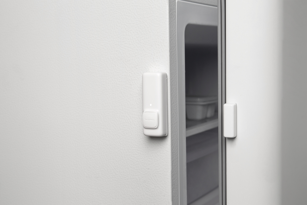 Ein Kühlschrank mit einem Türsensor. Der weiße Sensor befindet sich am Kühlschrank und an der Tür.