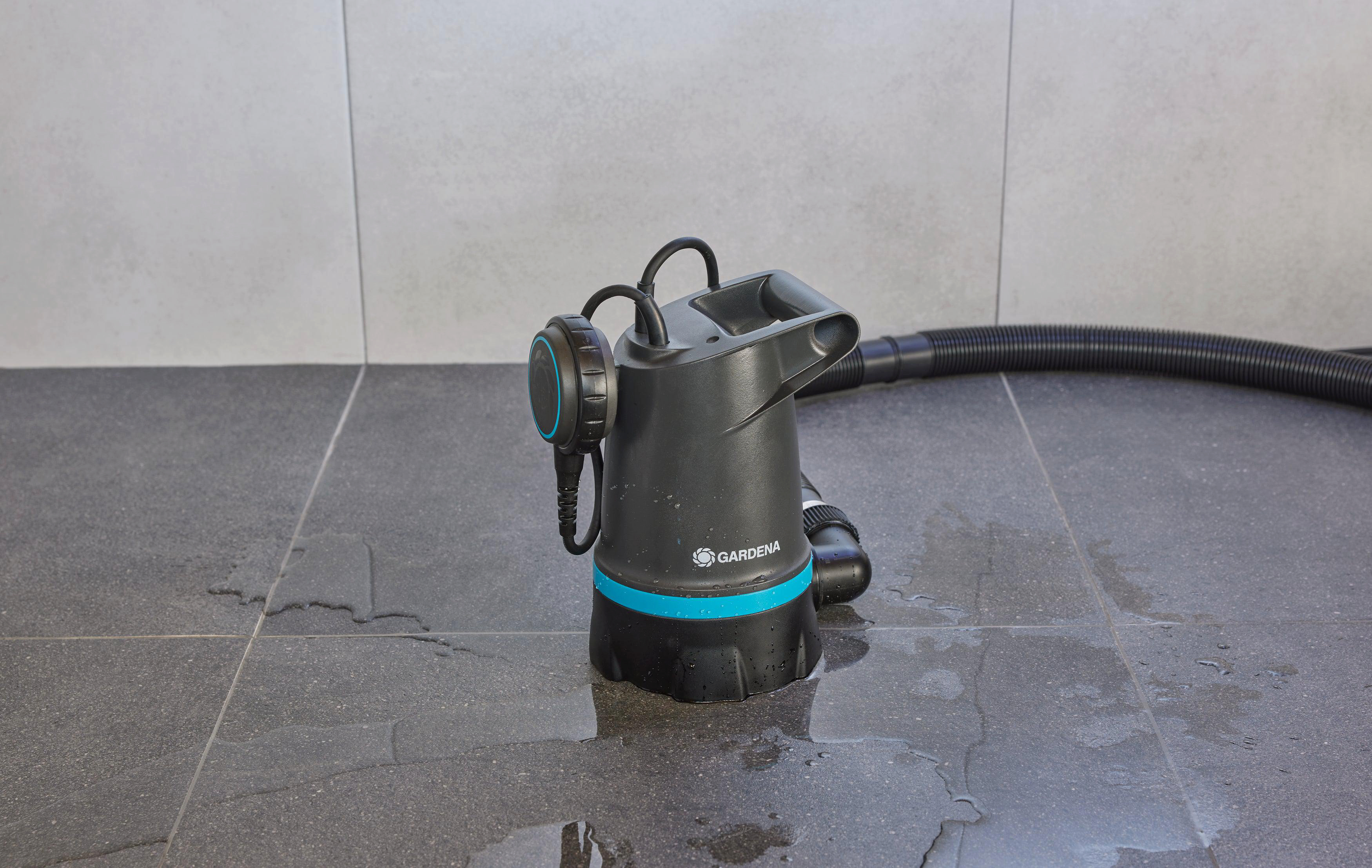 Eine Gardena-Pumpe steht in einem überfluteten Bereich. Wasser und grauer Hintergrund.