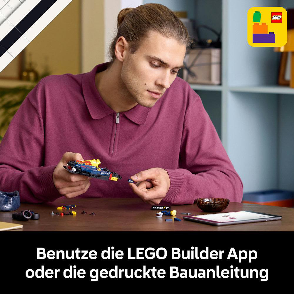 Mann, der ein LEGO-Rennauto zusammenbaut. LEGO-Box in der Ecke, Tablet auf dem Tisch. Deutscher Text.