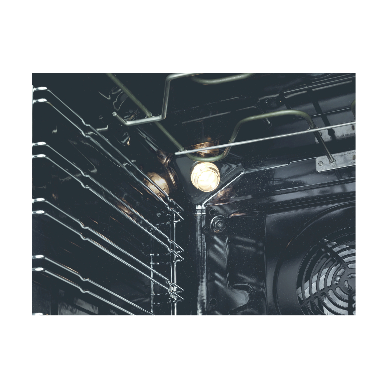 Interno di un forno, che mostra la lampadina, le griglie e la ventola, il tutto in un ambiente buio.