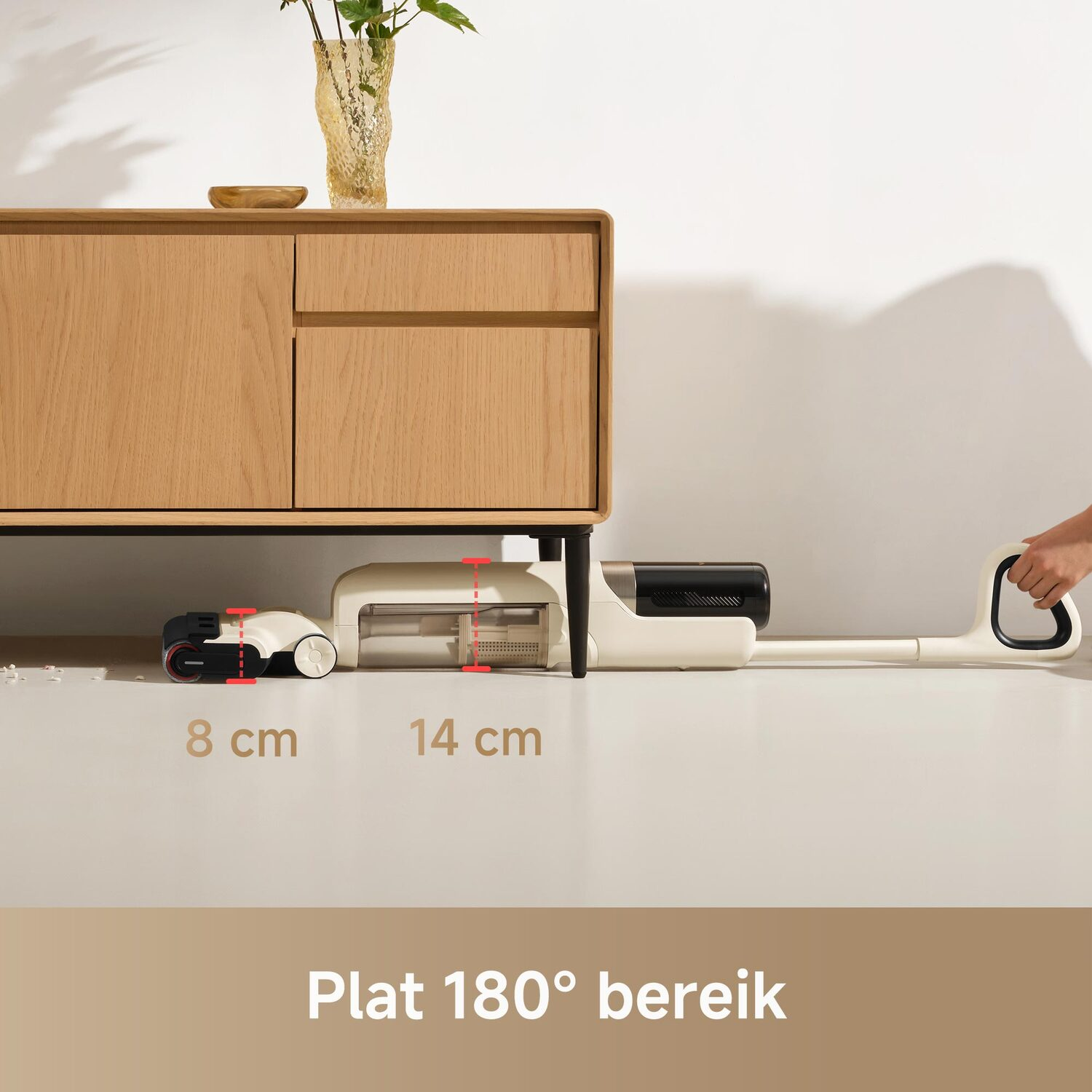 Een stofzuiger schuift onder een kast, met de reikwijdte en afmetingen.