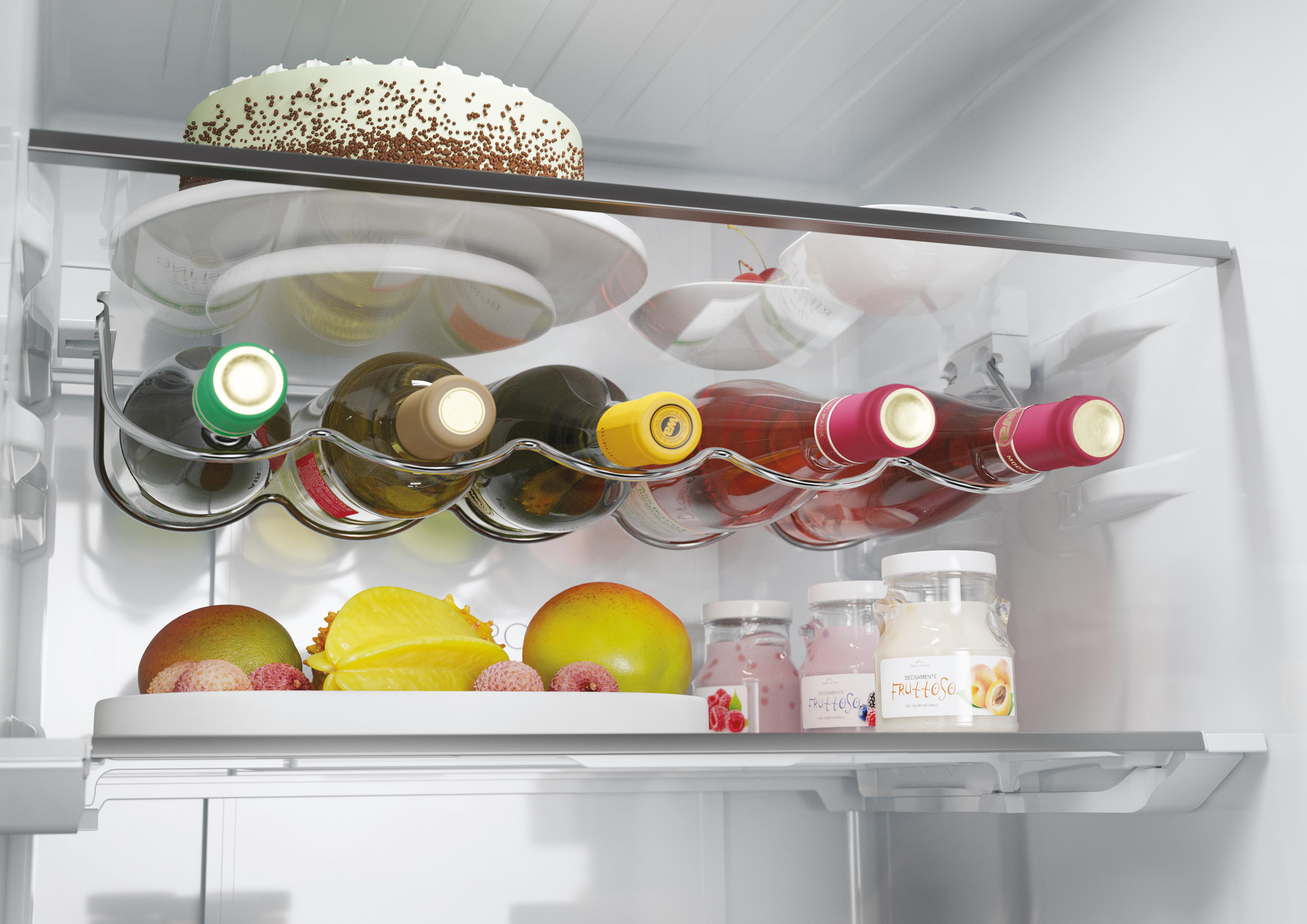 Im Kühlschrank. Weinflaschen, Gläser mit Fruchtaufstrich und Obst sind auf Regalen angeordnet.