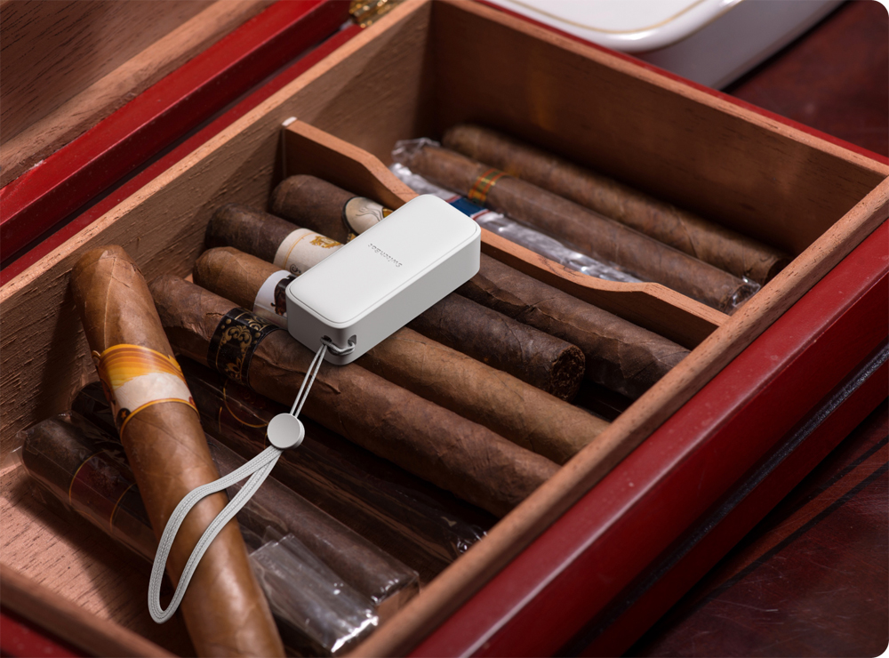 Zigarren und ein weißes Gerät in einem Humidor aus Holz.
