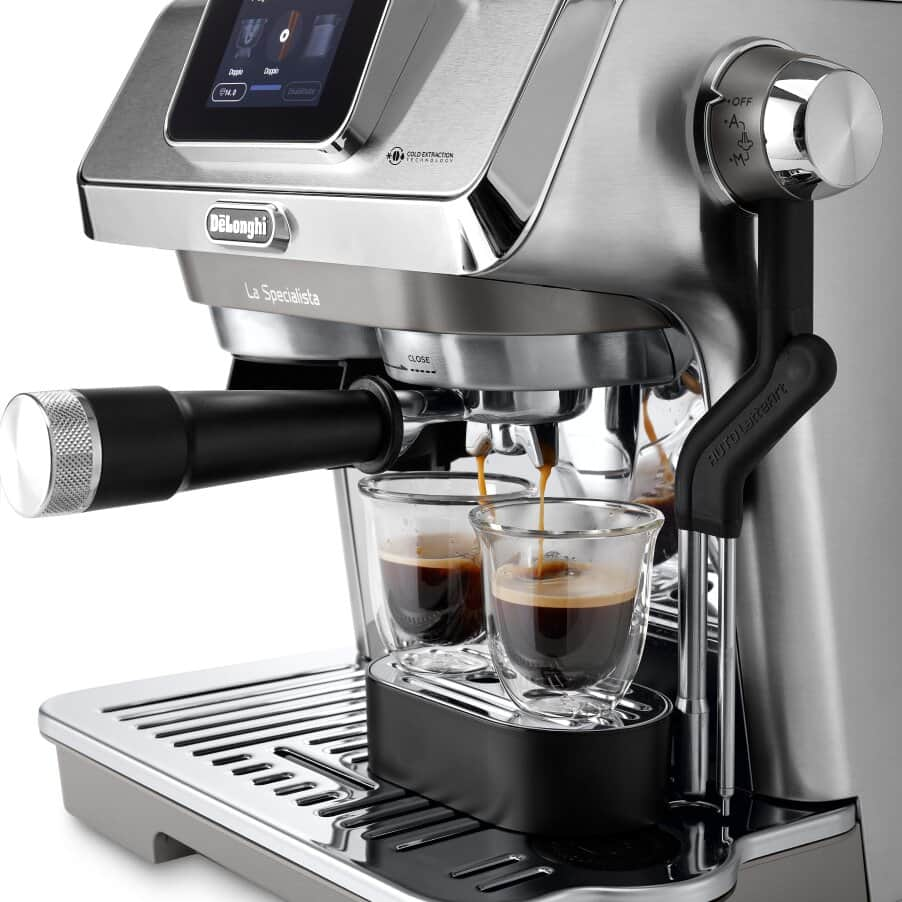 Espresszó gép, két pohárral, amelyek kávéval telnek, króm és fekete dizájn.