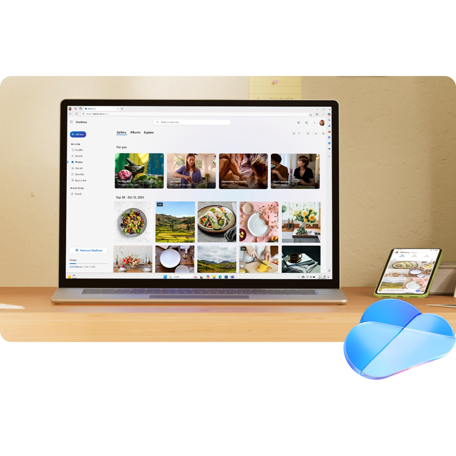 Laptop on a wooden desk, a smartphone beside it, and a cloud icon in the corner.