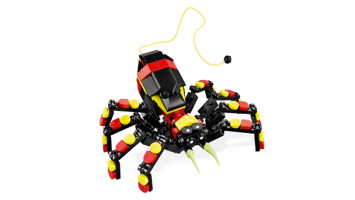 Zabawka Lego w kształcie skorpiona wykonana z czarnych, czerwonych, żółtych i zielonych klocków, na czarnym tle.