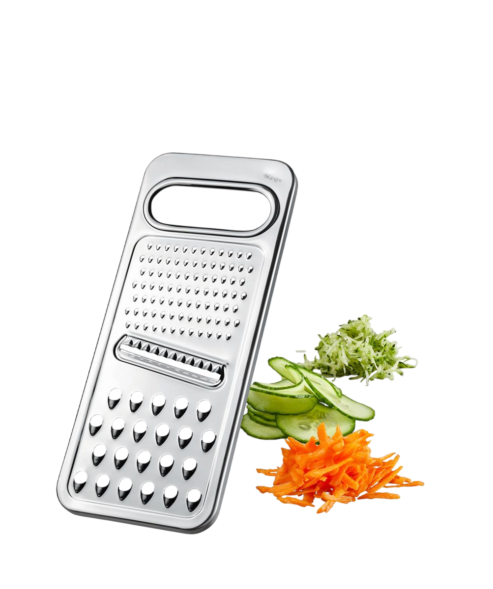 Ein glänzender Metallreibe mit geriebenen Karotten, Gurkenscheiben und geriebener Zucchini auf schwarzem Grund.