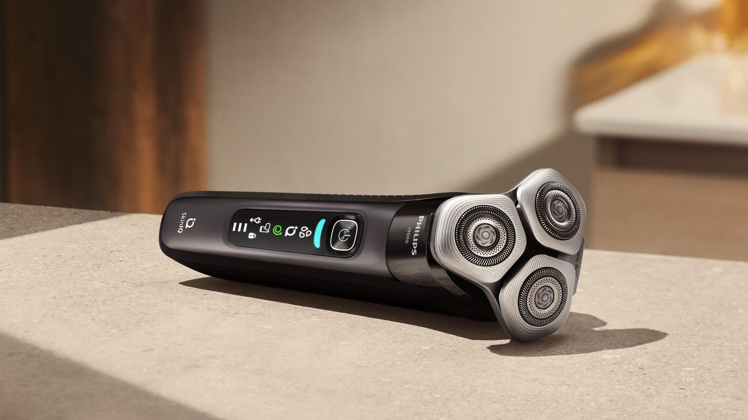 Schwarzer Elektrorasierer auf einer Stein Oberfläche. Der Rasierer hat drei rotierende Klingen und einen Ein-/Ausschalter.