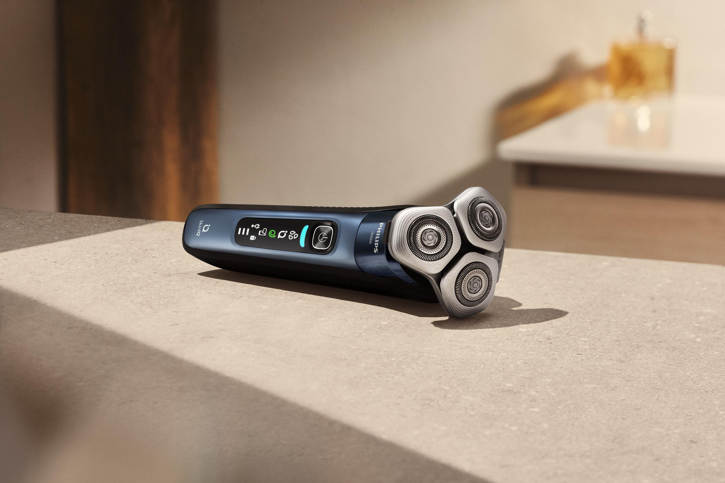 Ein schwarz-blauer Elektrorasierer auf heller Oberfläche, mit drei Scherköpfen.