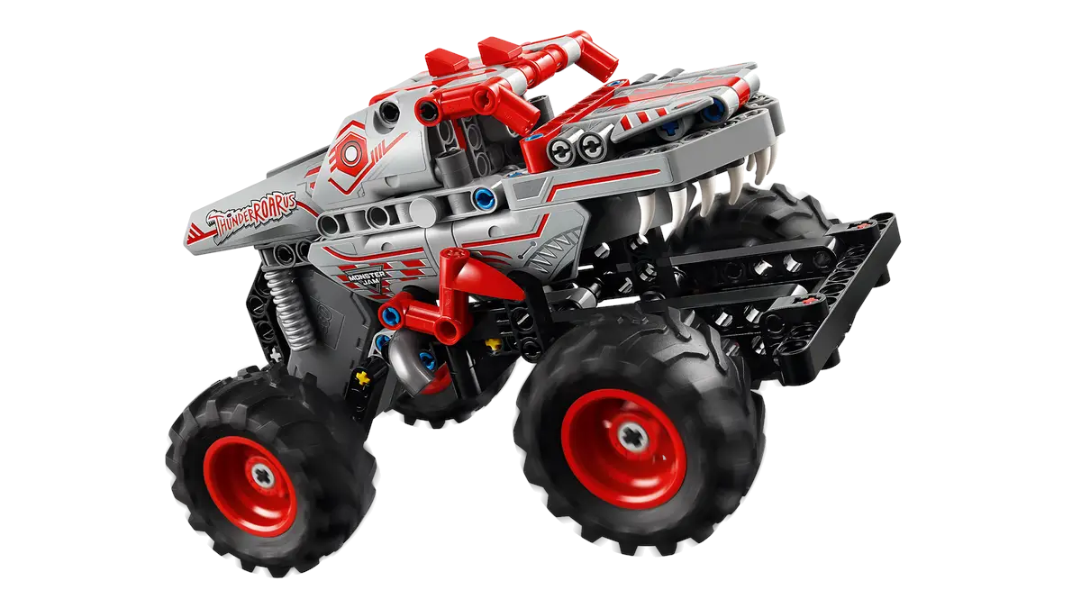 Zabawkowy monster truck, srebrny i czerwony, z dużymi czarnymi oponami.