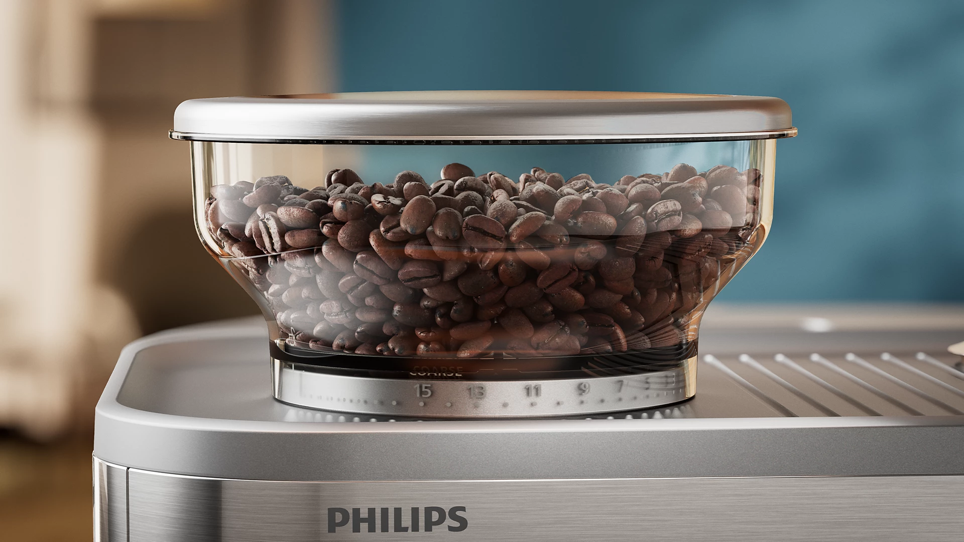 Un récipient en verre transparent rempli de grains de café est posé sur une machine à café argentée.
