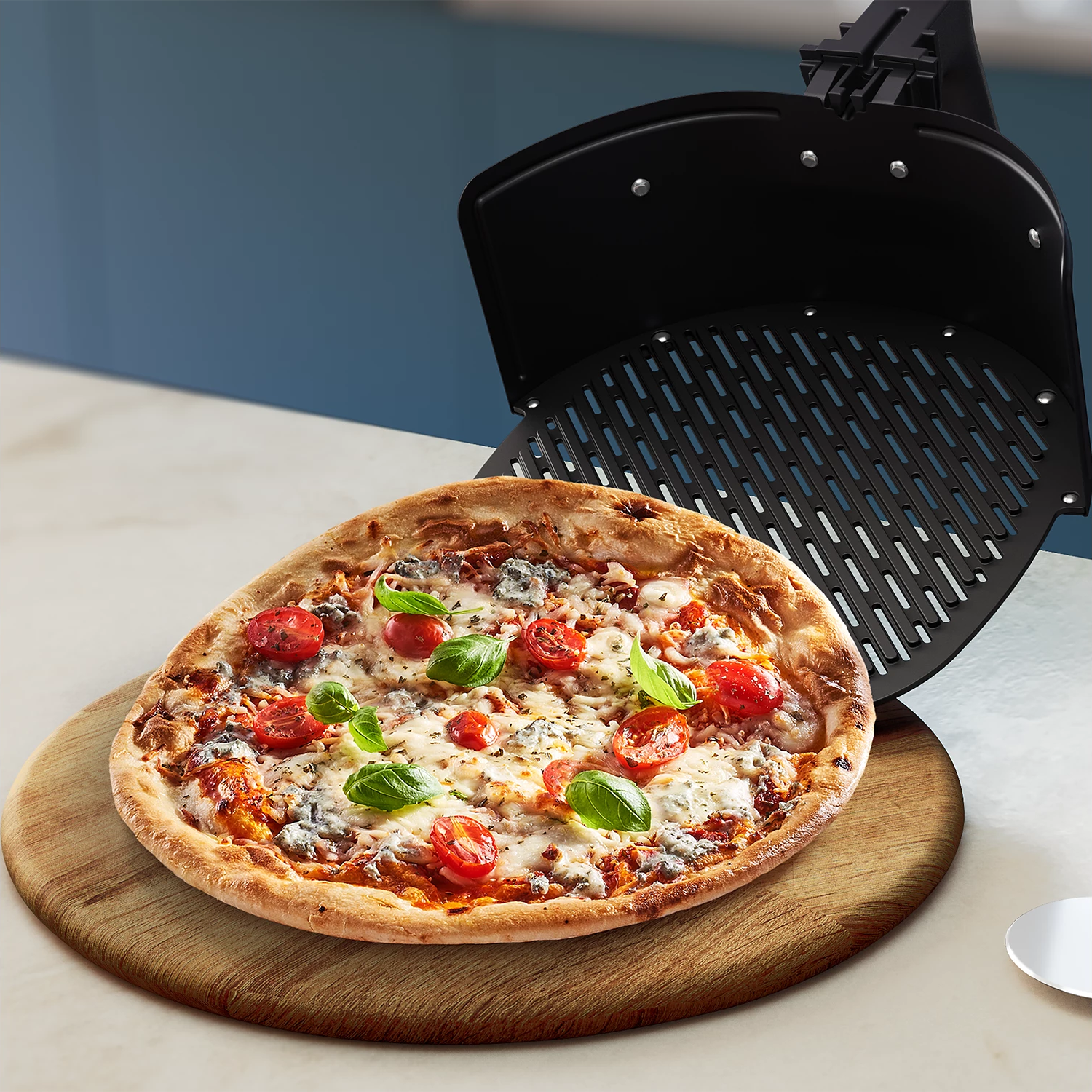 Pizza auf einem Holzbrett mit einer Heißluftfritteuse im Hintergrund.