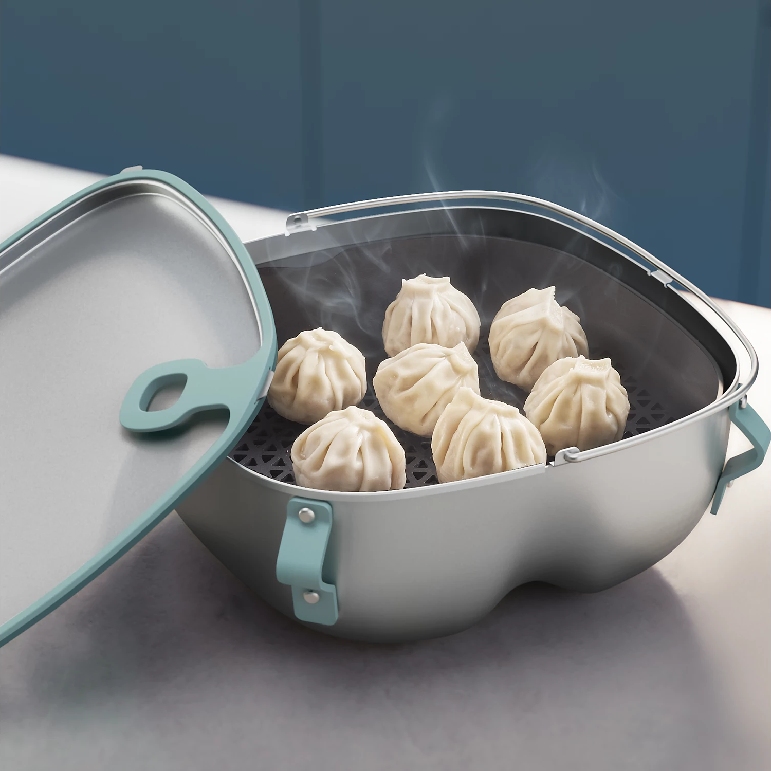 Dampfende Knödel in einem grau-blauen Kochbehälter mit geöffnetem Deckel.