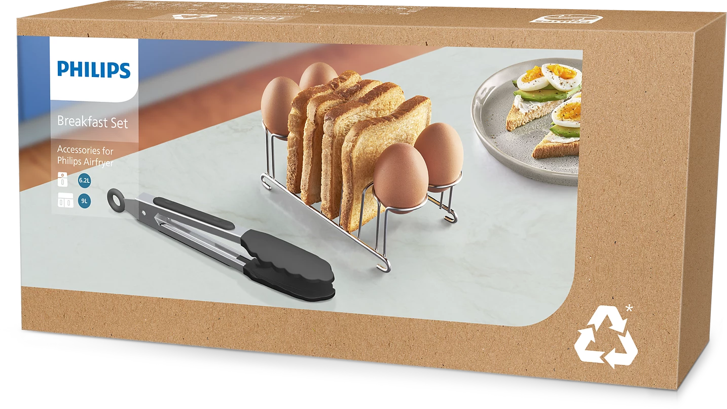 Karton mit Frühstücks-Set: Eier, Toast, Zange und Messer.