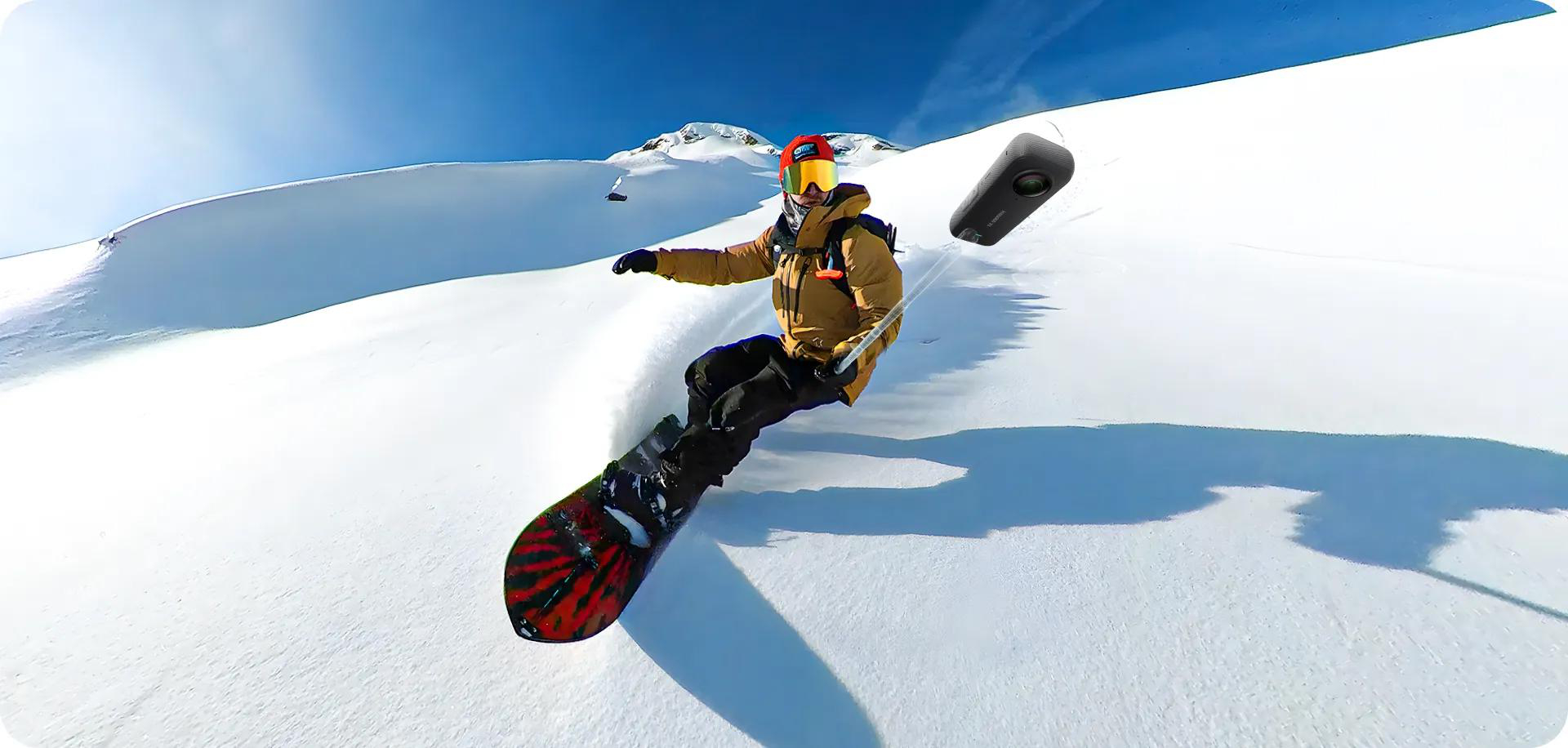 Snowboarder in einem schneebedeckten Berg, mit einer Kamera an einem Selfie-Stick in der Luft.