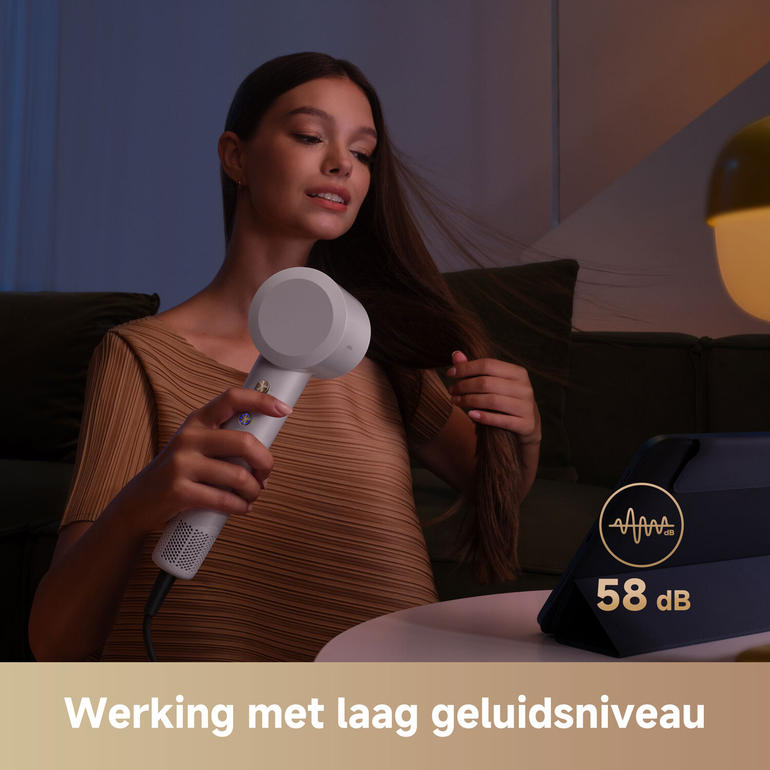 Vrouw die een witte föhn gebruikt. Een tablet toont 58 dB. Tekst zegt: 'Werken met weinig lawaai'.